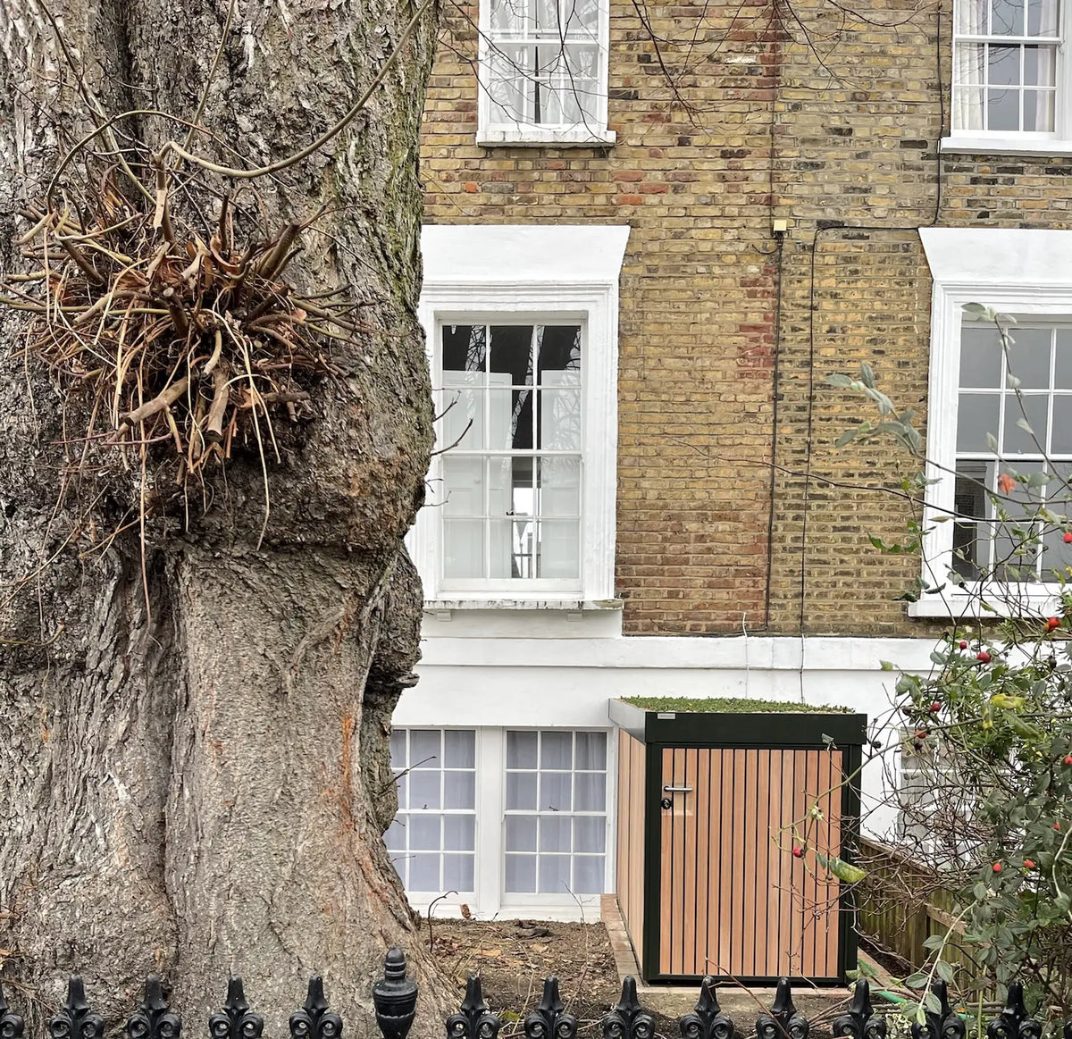 Street view image of a bespoke Verde Uno with an extensive green roof extension above a vertical bike rack.