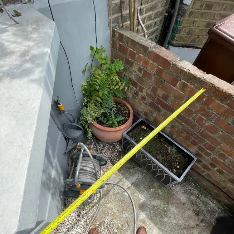 Front garden bay window area cluttered with hose, tap and modem, showing an awkward space that cannot be used properly.