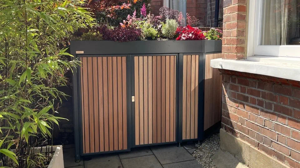 Bespoke front garden storage in a London conservation area, wrapped around a bay window with hardwood cladding, planted green roof and steps following the garden slope.