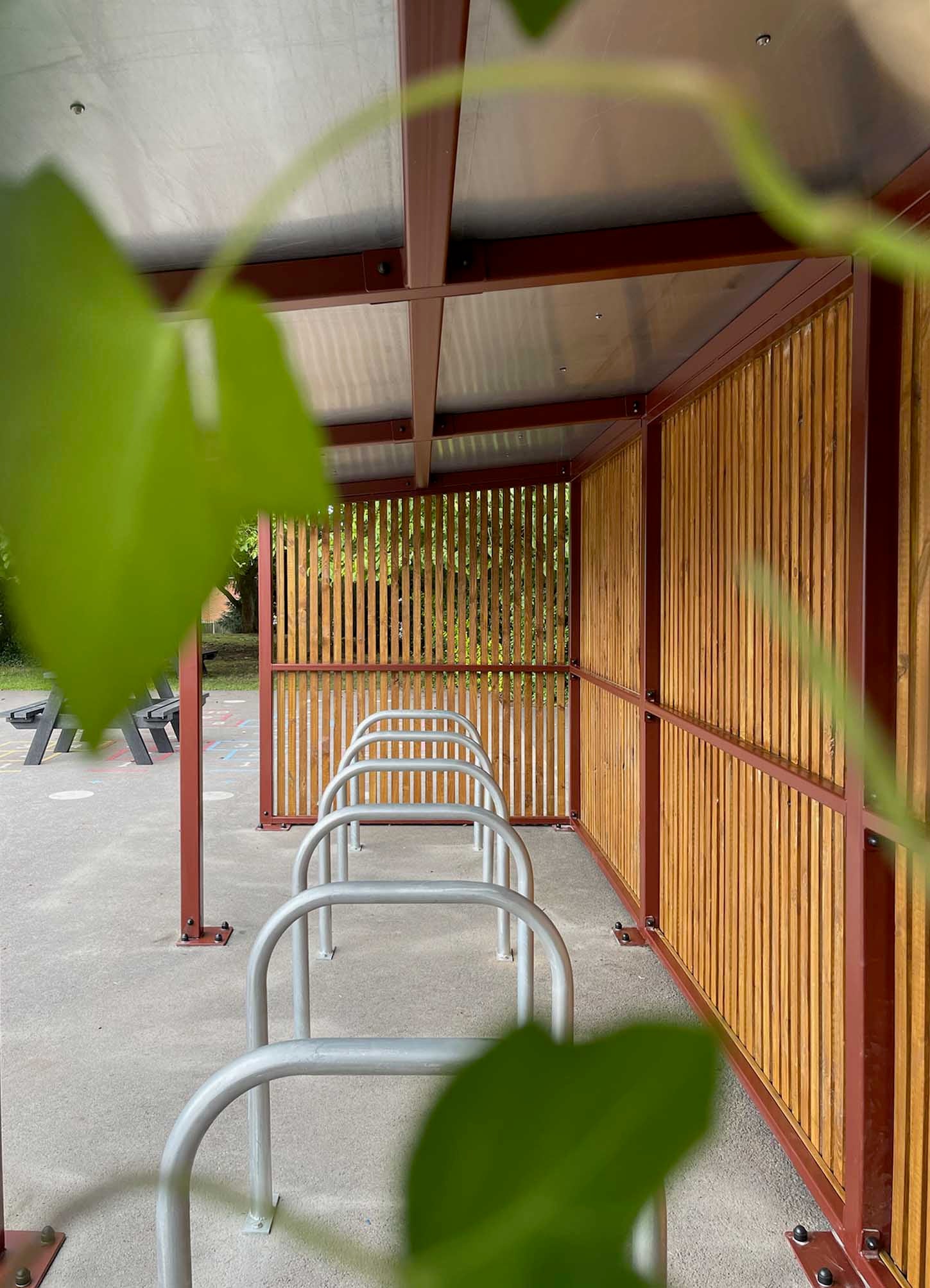 Bike shelter with treated timber cladding and green roof, aligning with BREEAM and BNG certifications to enhance biodiversity and environmental well-being.