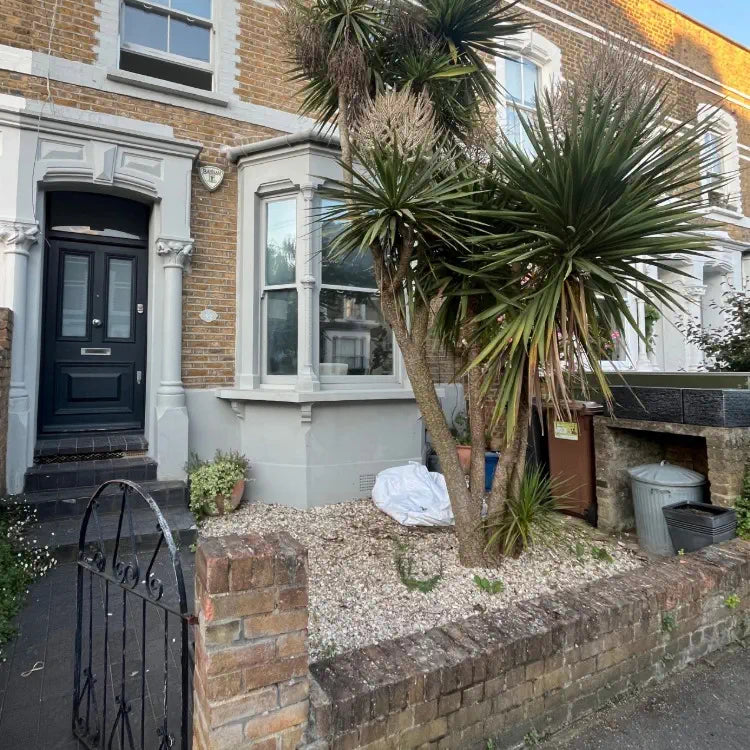 Front garden cluttered with bins, plants and gravel, leaving no open space to enjoy.
