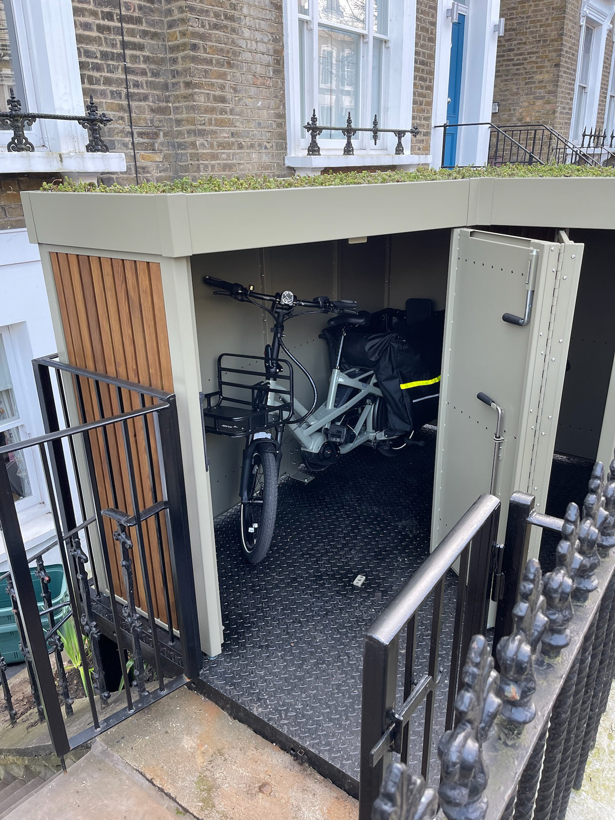 Custom double-hinged door design on cargo bike storage unit allowing effortless manoeuvring and accessibility, detail view with visible cargo bike