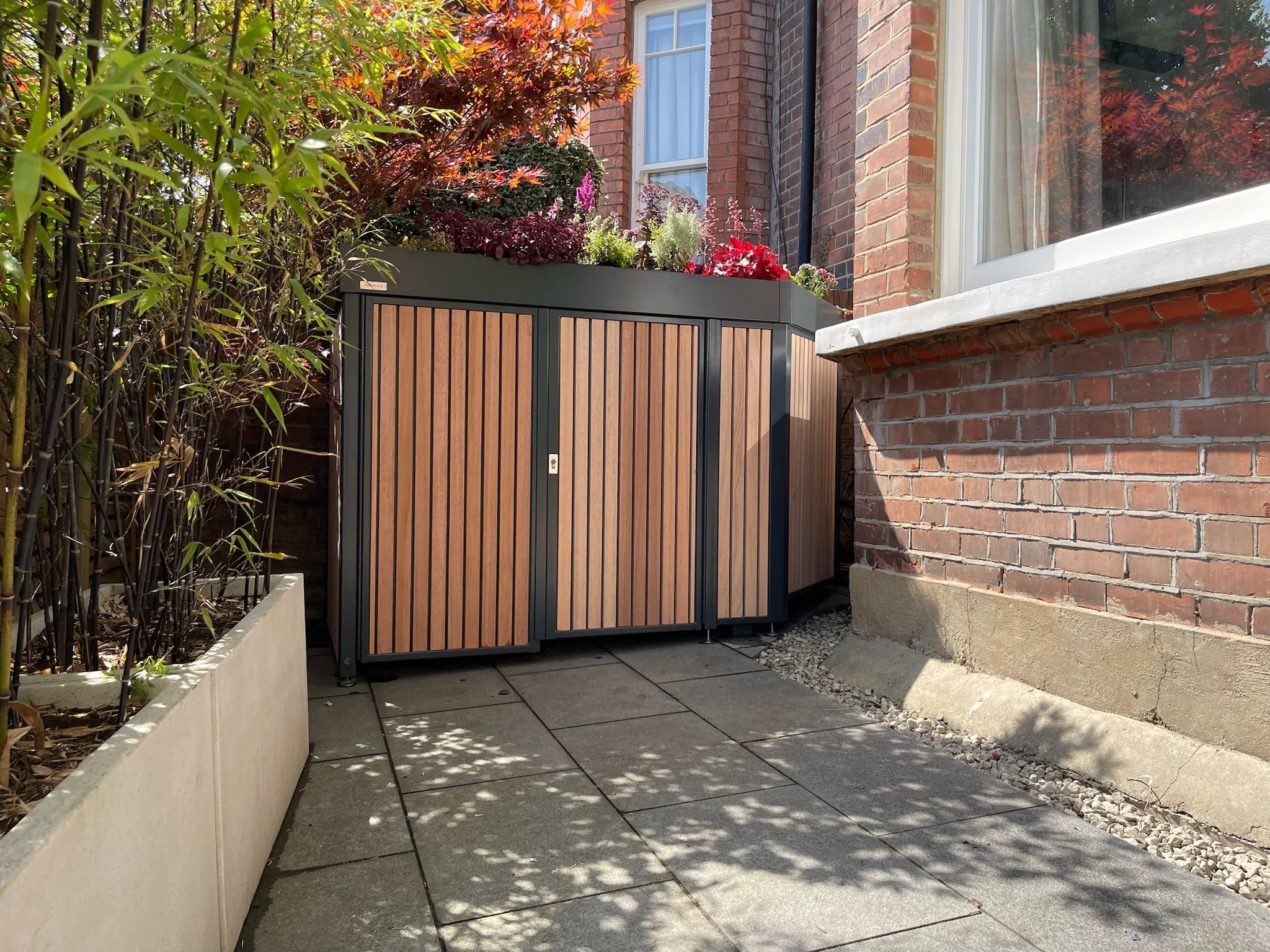 Secure Front Garden Storage for London Homeowners, bike shed wrapped around bay window, fits up to 5 bikes, with rich biodiverse planted roof with hardwood  timber cladding.