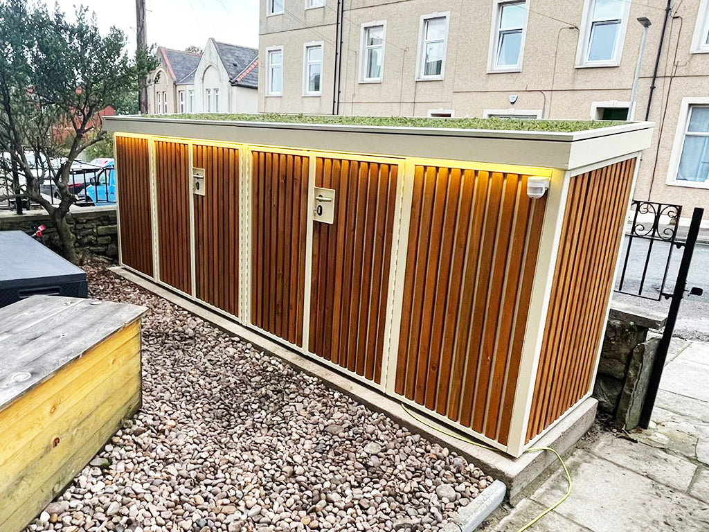 Secure bike storage unit featuring a green roof, offering protection for bicycles while adding greenery to the outdoor space, for daily commuters and expensive bikes
