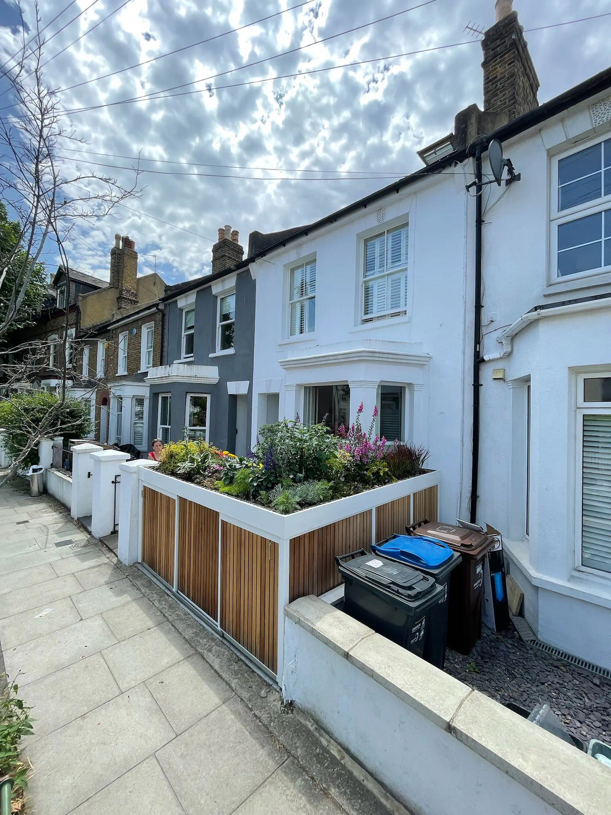 Full view from the street of a bespoke bin and bike store with a prominent planted green roof.