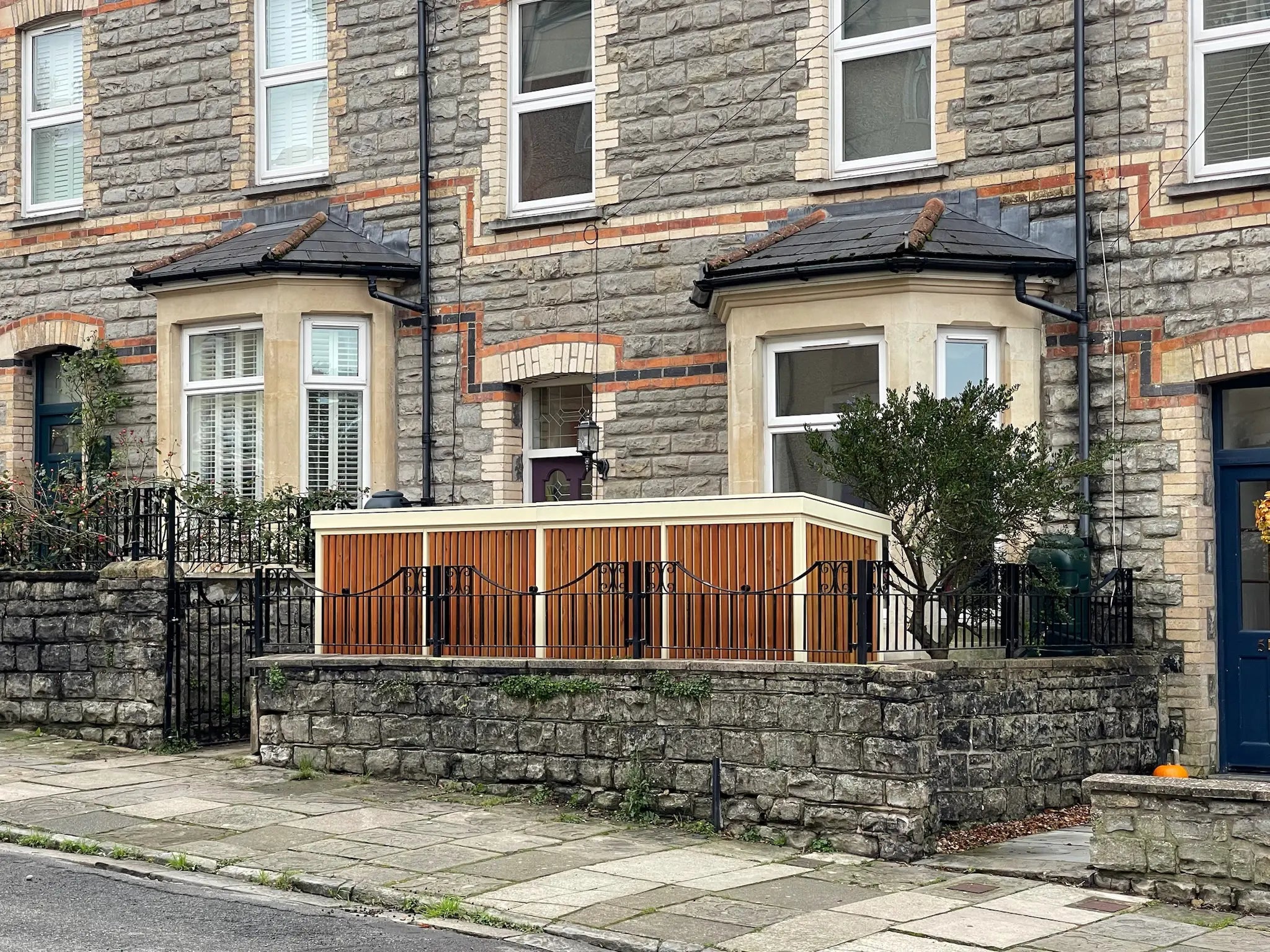 Sidewalk view of Verde Plus bike shed featuring sandy-coloured structure and timber cladding