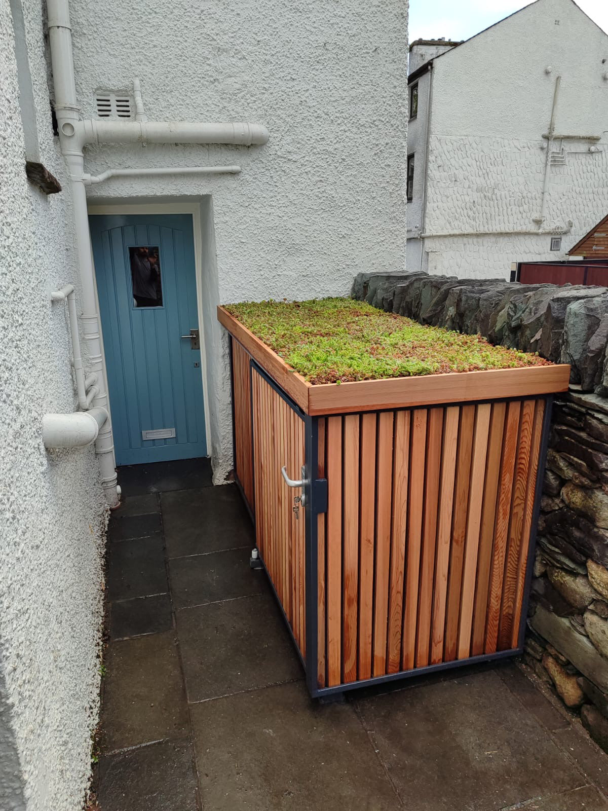 Verde Uno compact bike store with timber cladding, green roof, and sliding door closed.