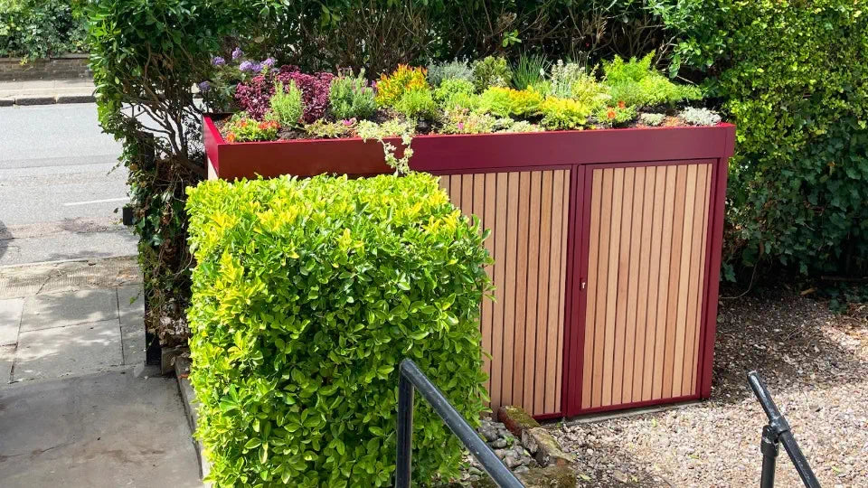 Wine red bike and bin store with a luxurious planted green roof, elegant colour and premium design for a front garden