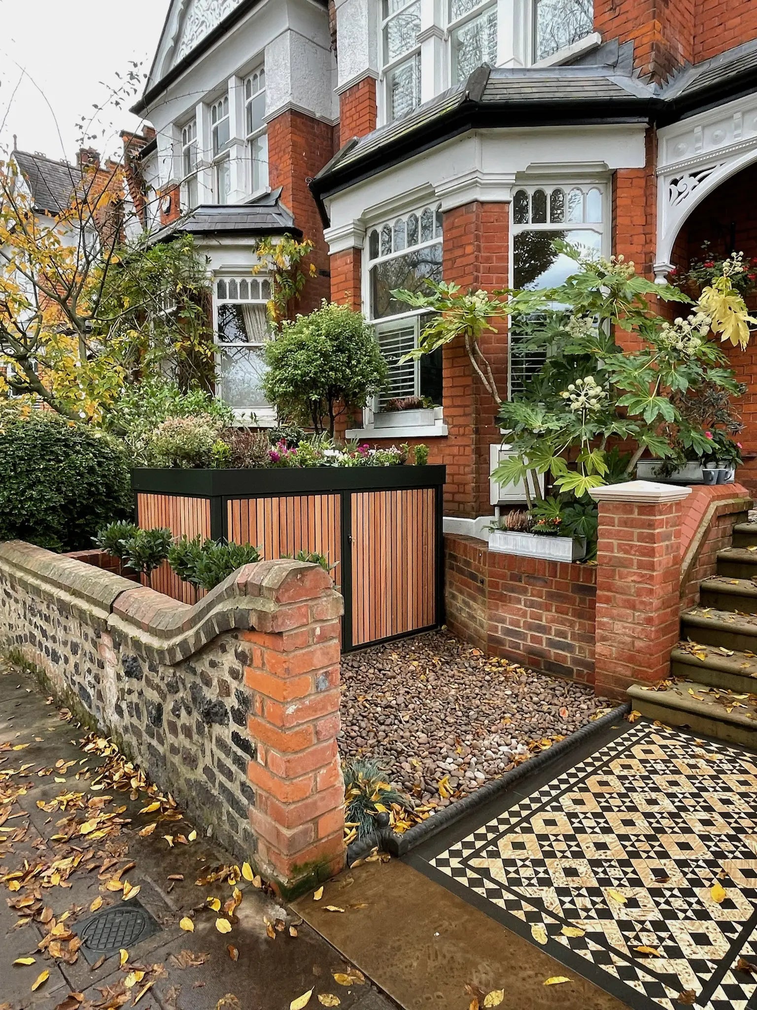 After image of deep green bike store with timber cladding and planted roof integrated into a stepped front garden