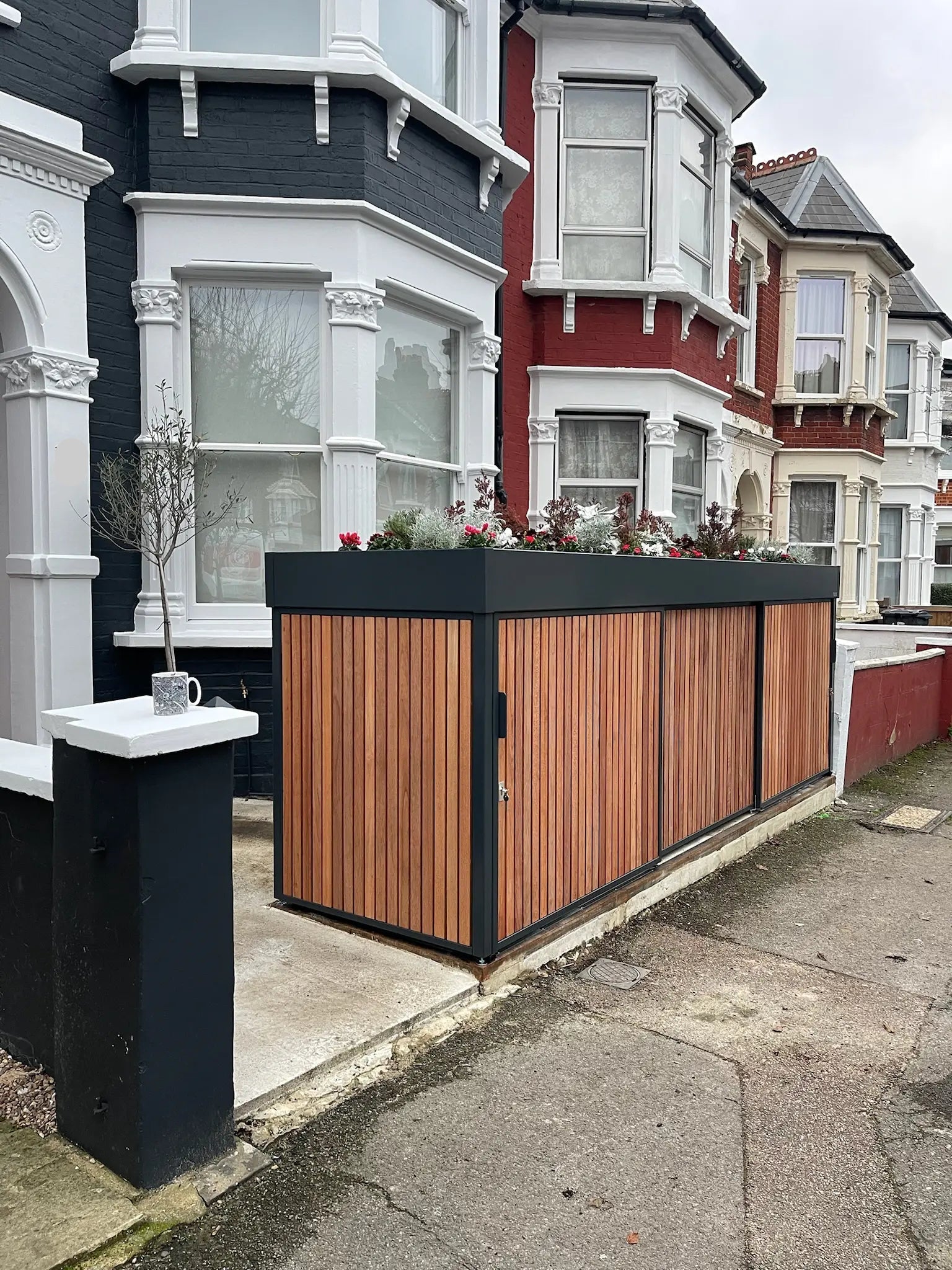 After image of slim anthracite grey bike and bin store with sliding doors and planted roof replacing the front wall in a London front garden