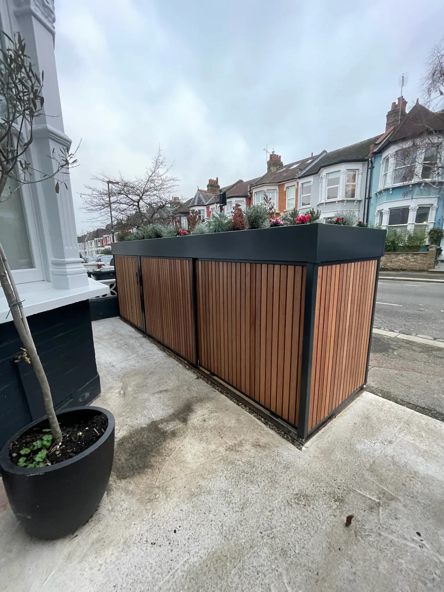 View from house entrance showing closed anthracite grey bike store replacing the front wall in a London front garden