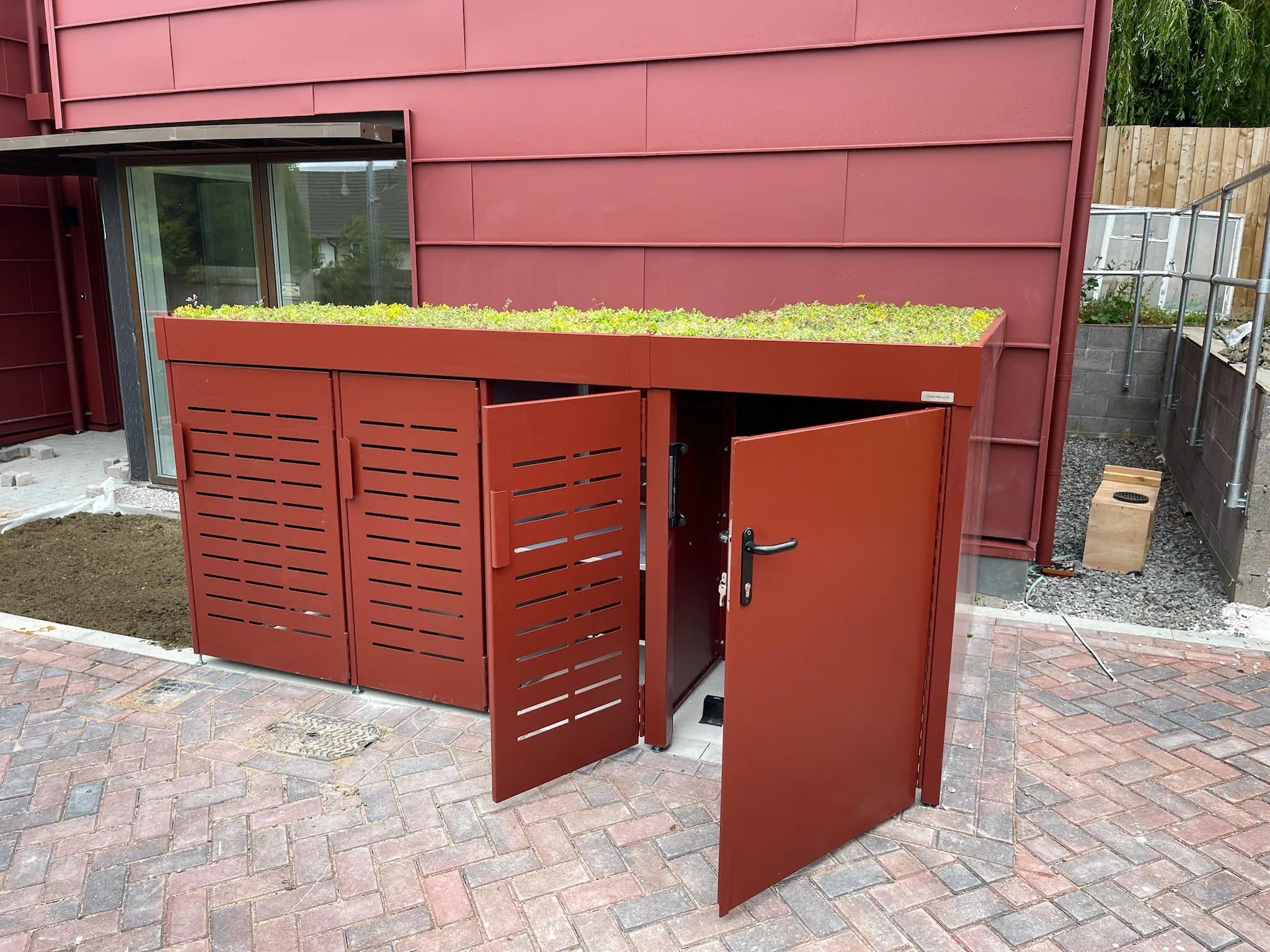 Front view of bespoke bike and bin storage with cycle and waste stores open, showing cycle and refuse access — secure green roof solution for London homeowners.