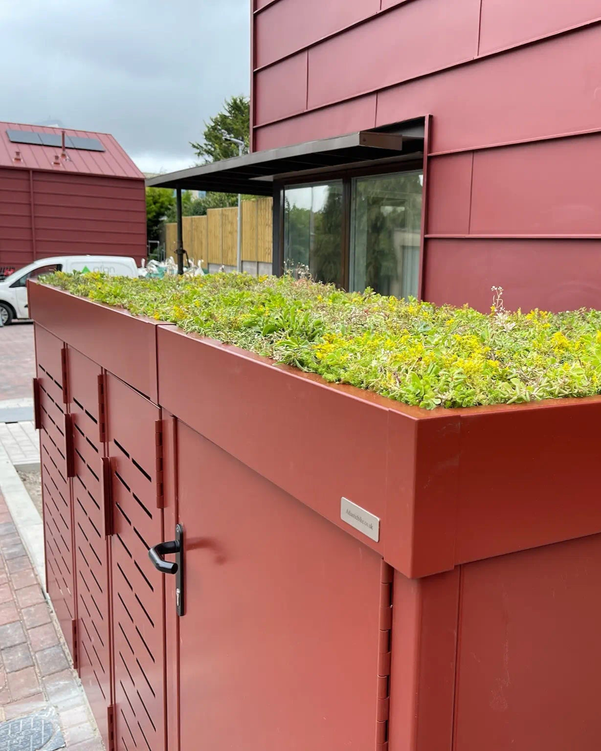 Overhead view of continuous planted roof across cycle and refuse storage units — elegant integration of greenery into London urban homes.