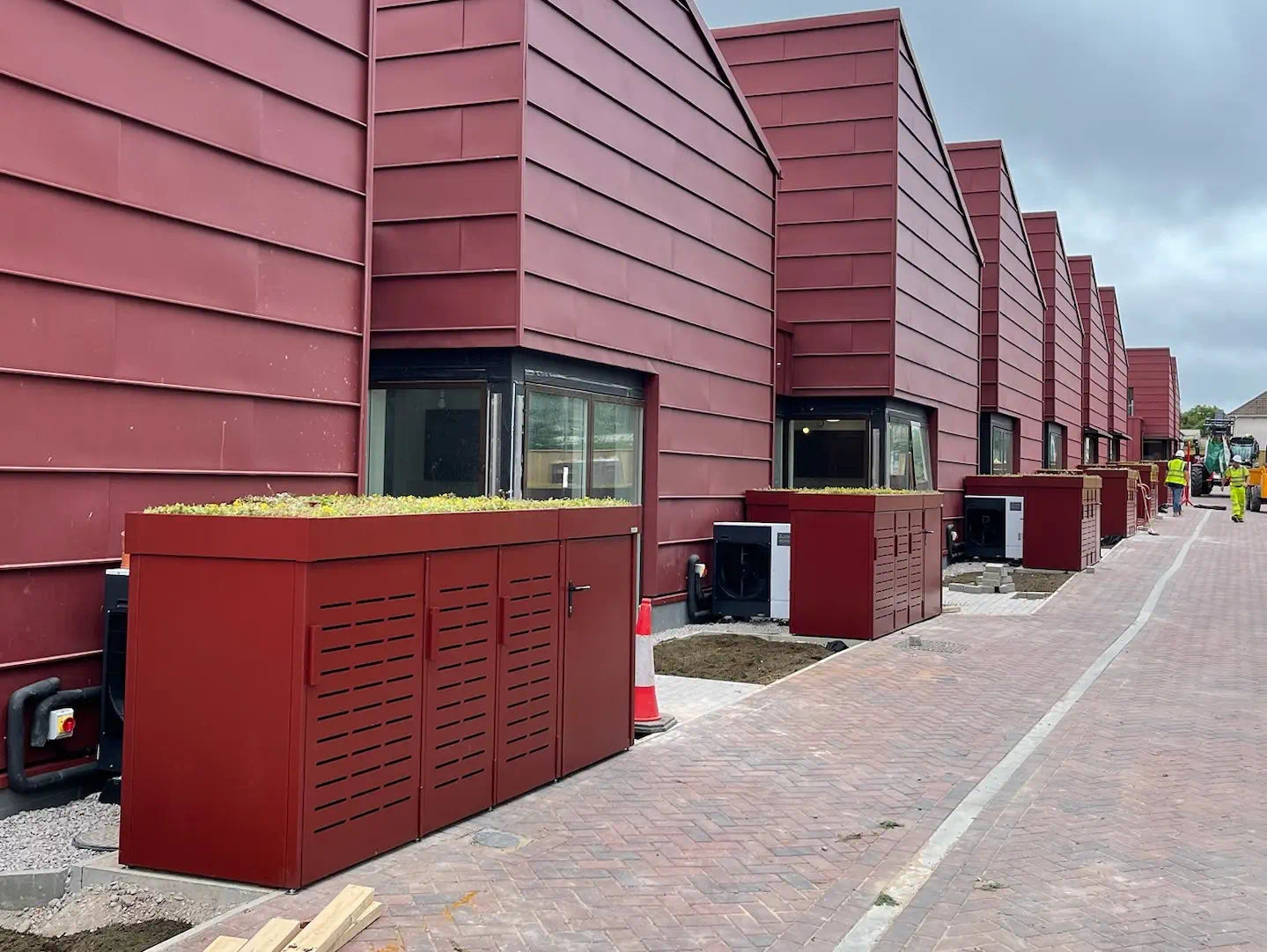 Wide view showing series of nine integrated bike and bin stores with green roofs — scalable, secure storage for residential developments.