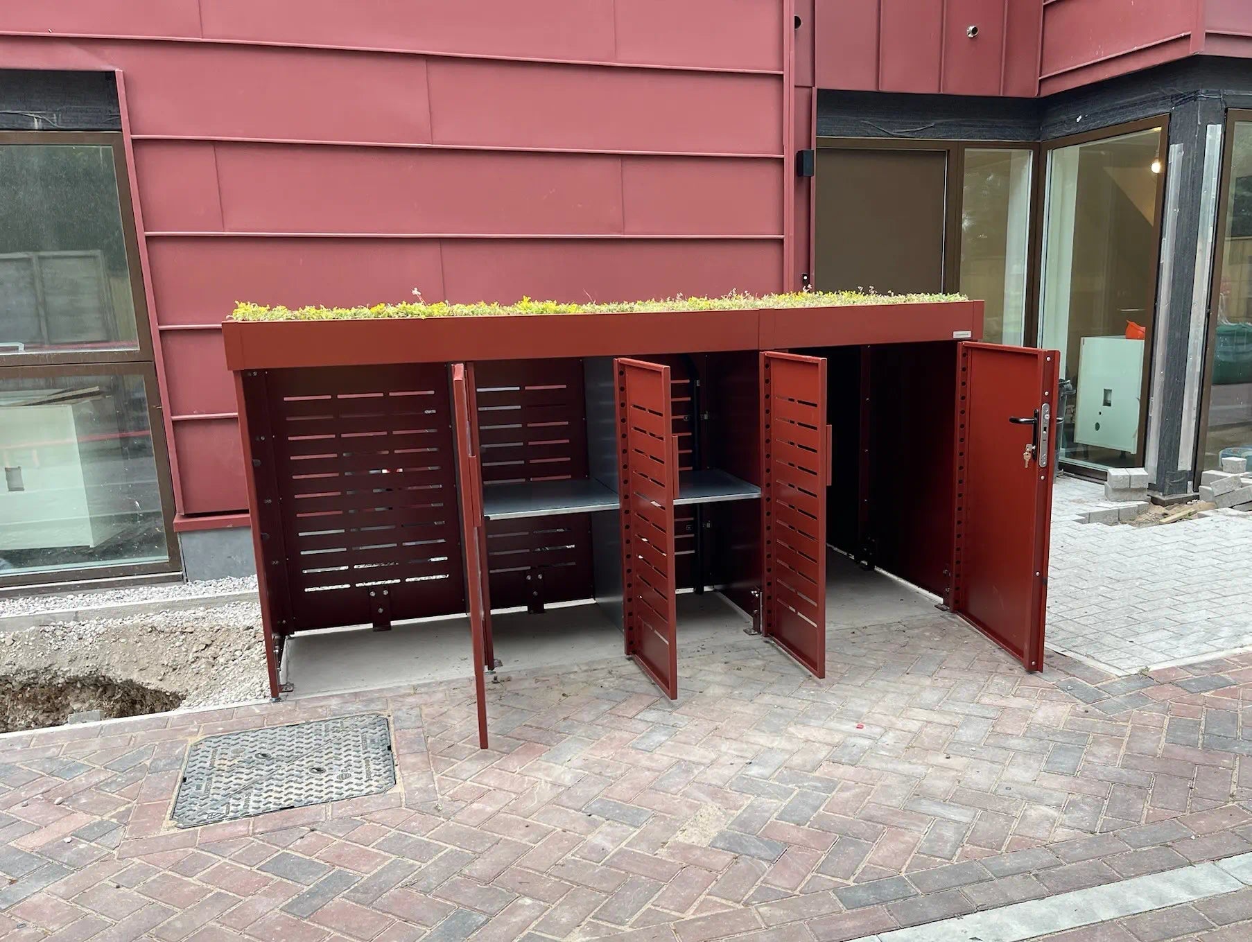 Front view of bespoke bike and bin storage with all compartments open, showing cycle and refuse access — secure green roof solution for London homeowners.