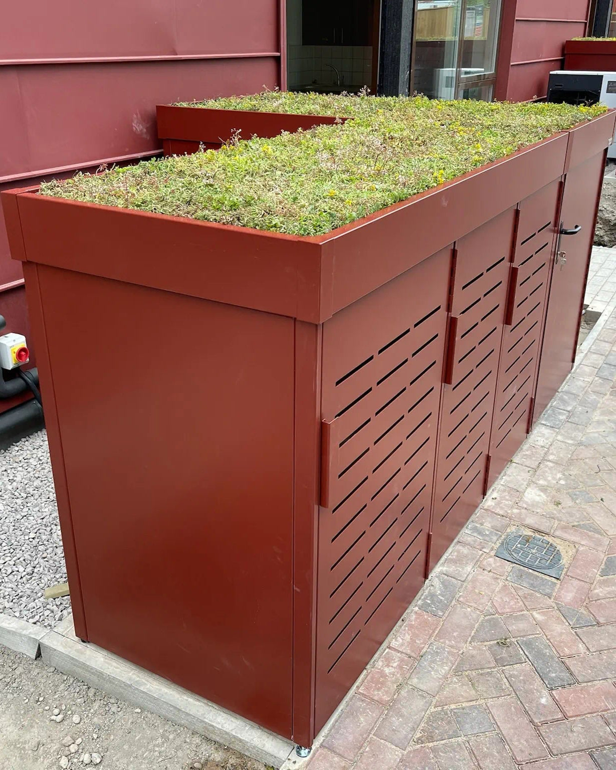 Detail of sedum planted green roof — pollinator-friendly, low-maintenance roofing on secure metal bike and bin storage.
