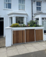 Closed white bin and bike store with sliding doors and a lush planted green roof, viewed from the street.
