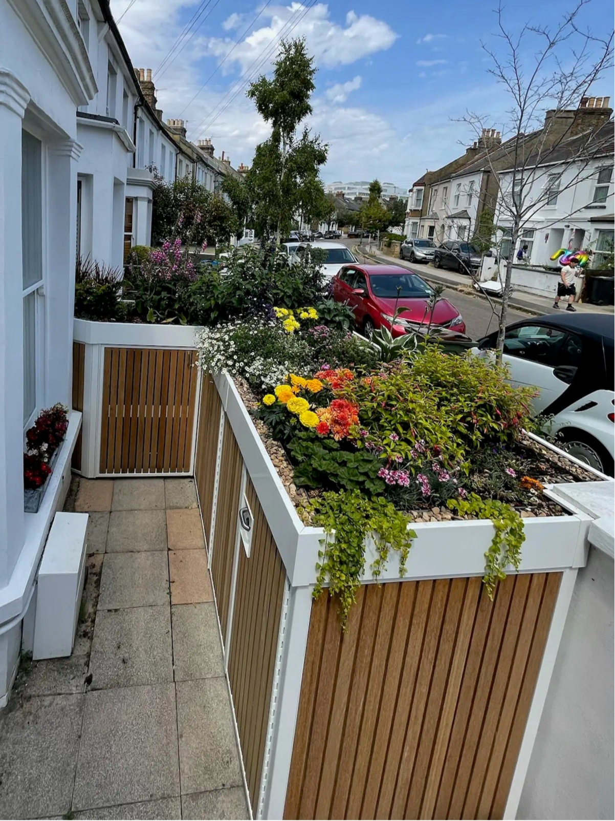 Custom sliding-door bike and bin store wrapping neatly around a bay window, maximising tight front garden space.