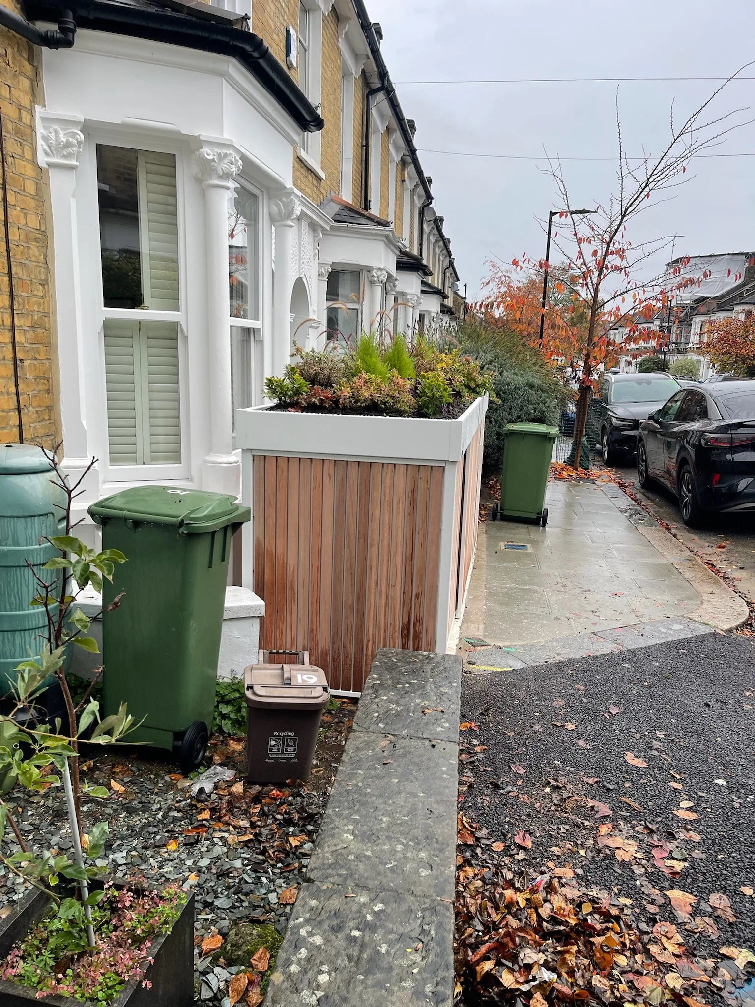 Left-side view of discreet bin storage integrated into front garden cycle store.