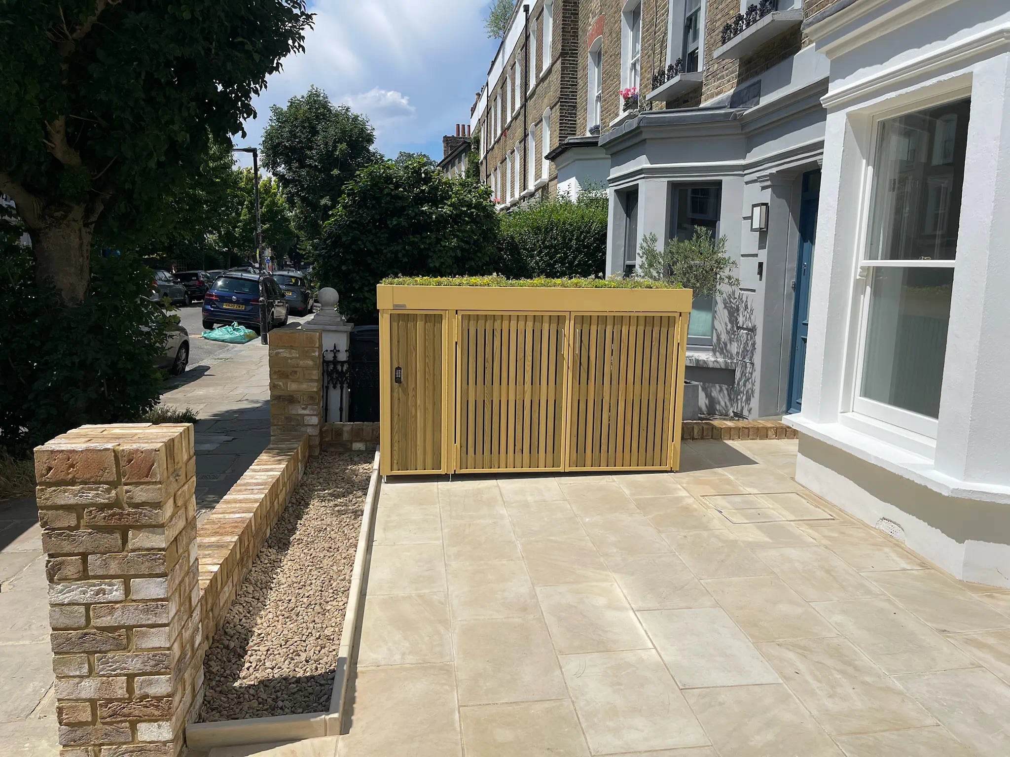 Timber-clad front garden outdoor storage unit with green roof and closed doors.