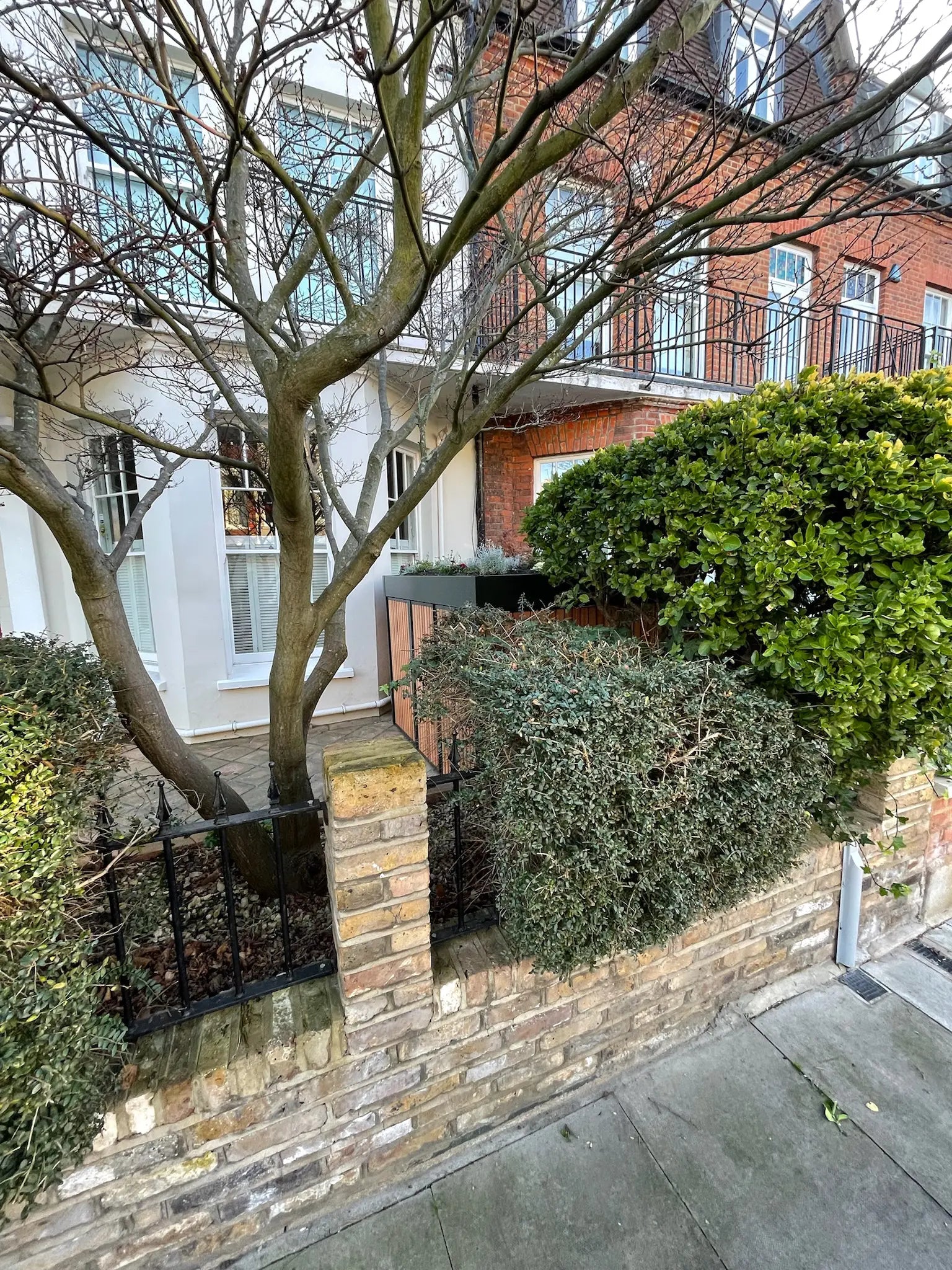 Concealed street view of deep green side bike store, designed to blend into a conservation area streetscape