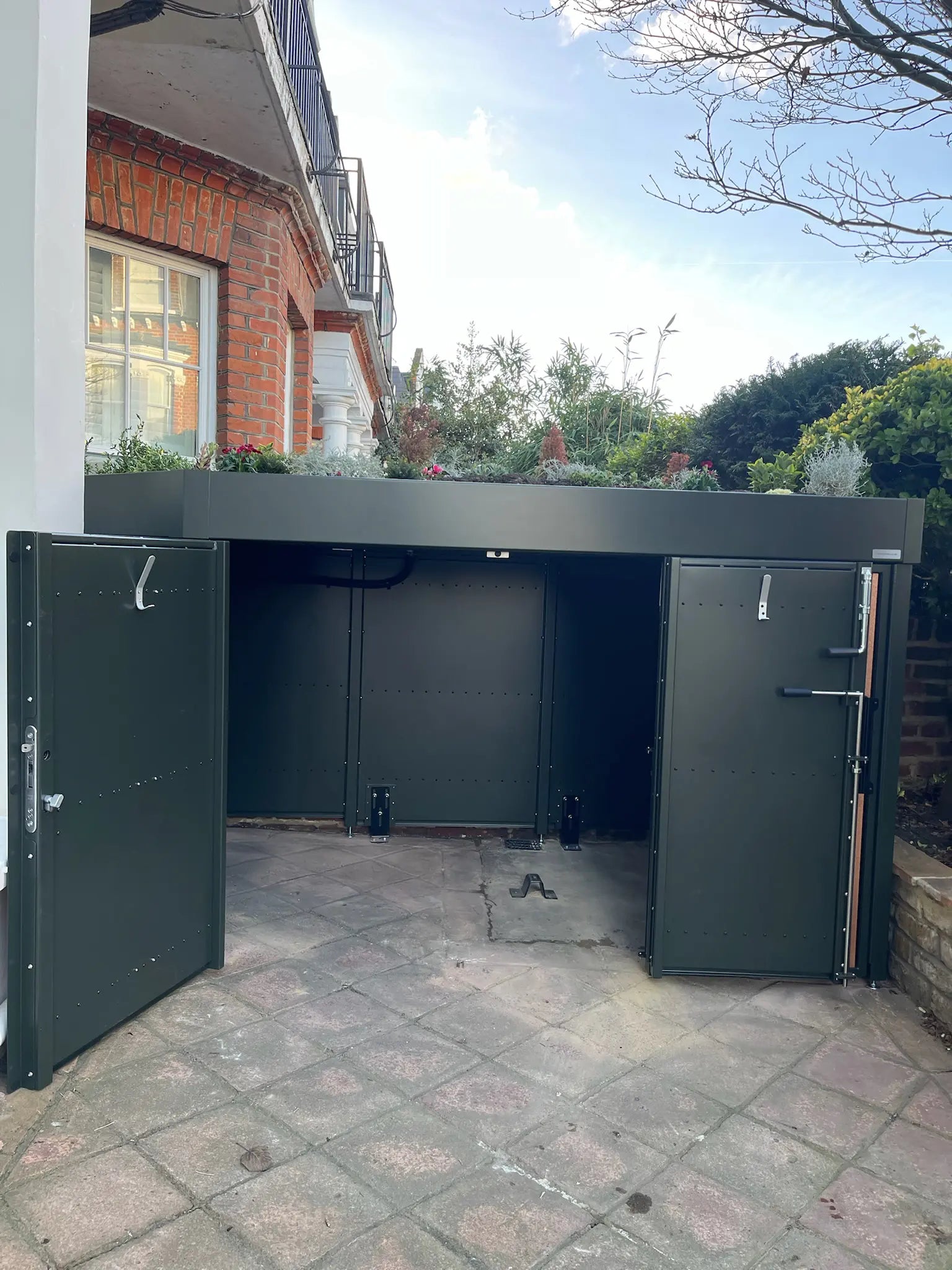 Partially open deep green bike store showing smooth access and generous internal storage capacity