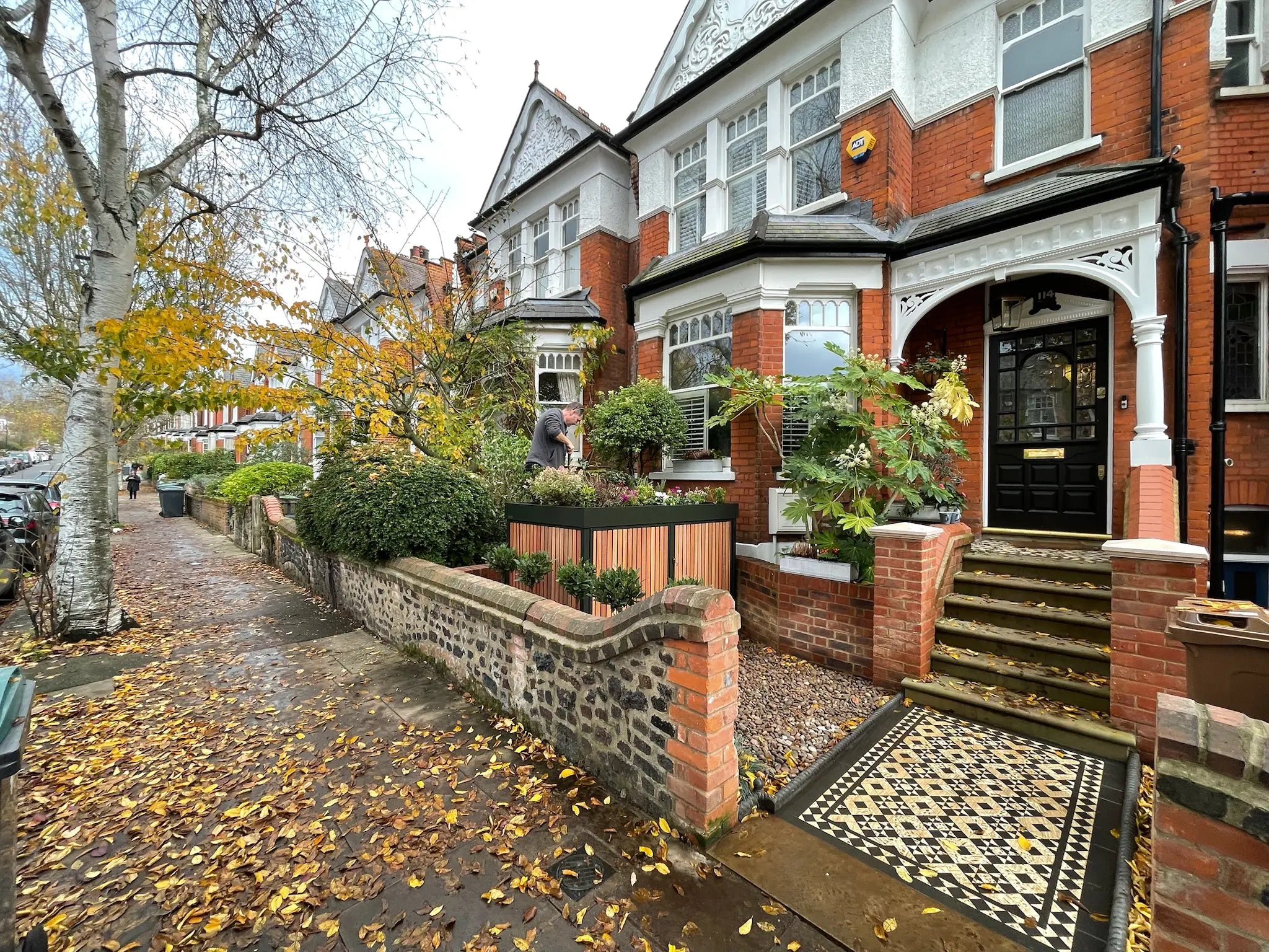 Street view from the right of deep green front garden bike store with timber cladding in a characterful London frontage