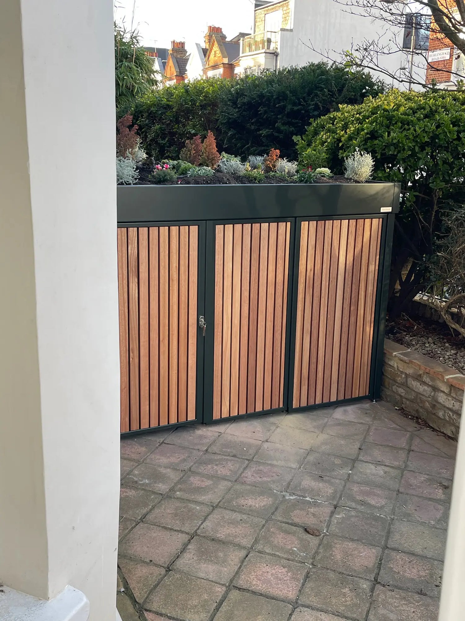 House-side view of deep green bike store occupying the full depth of a front garden in a Hammersmith conservation area