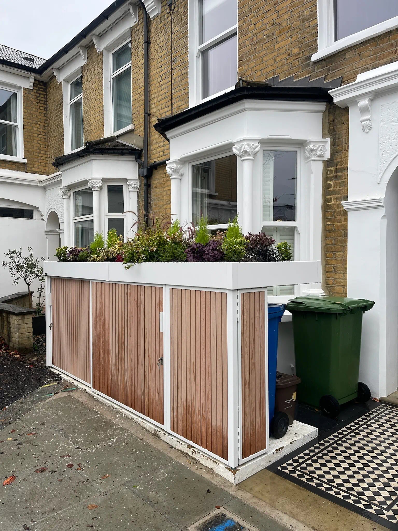 Angled street-side view of compact bike store with concealed bin storage panel in London front garden.