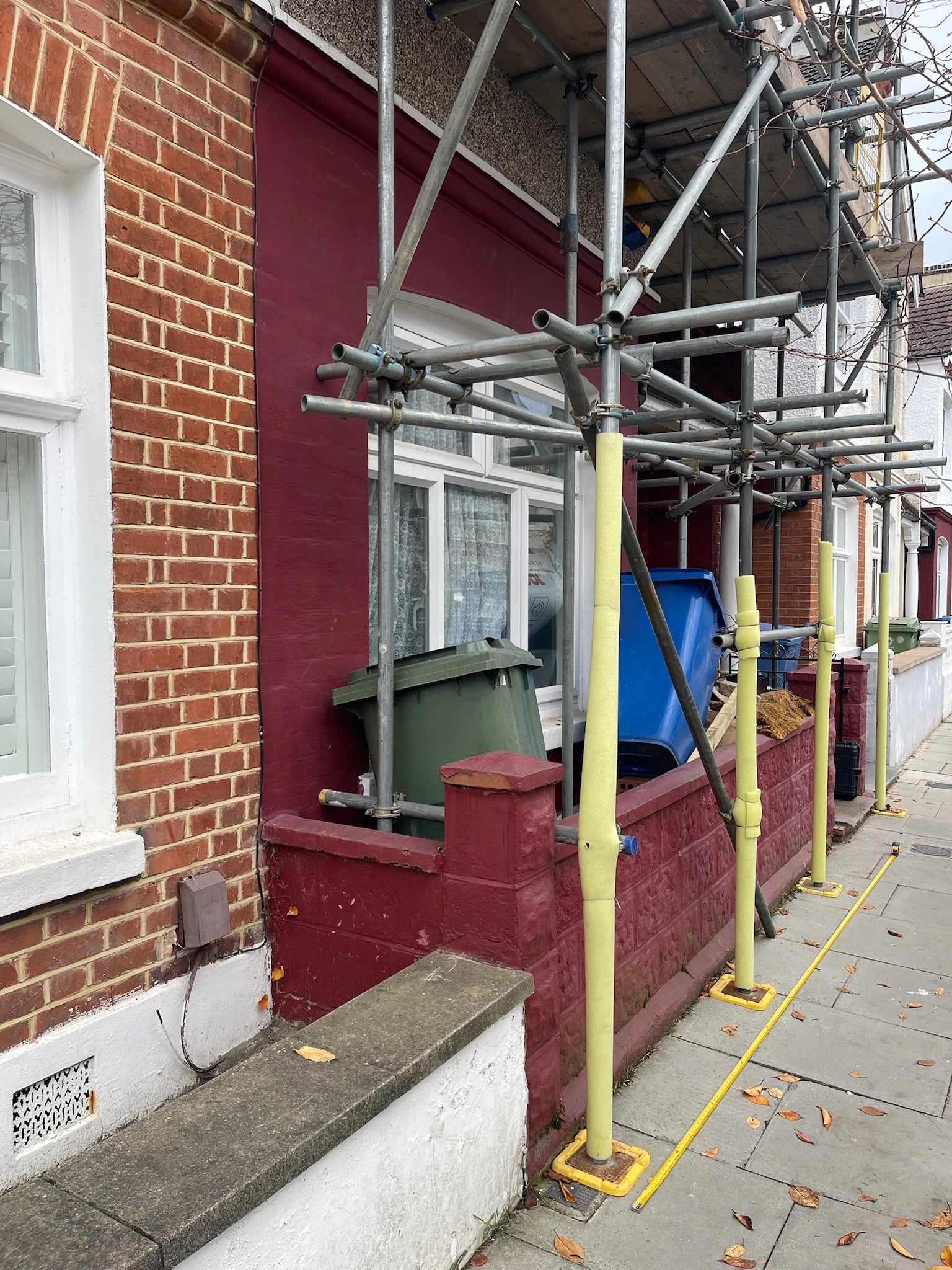 Before: boundary wall of a London terrace under scaffolding, with bins stored against the wall ahead of a front garden bike and bin store.