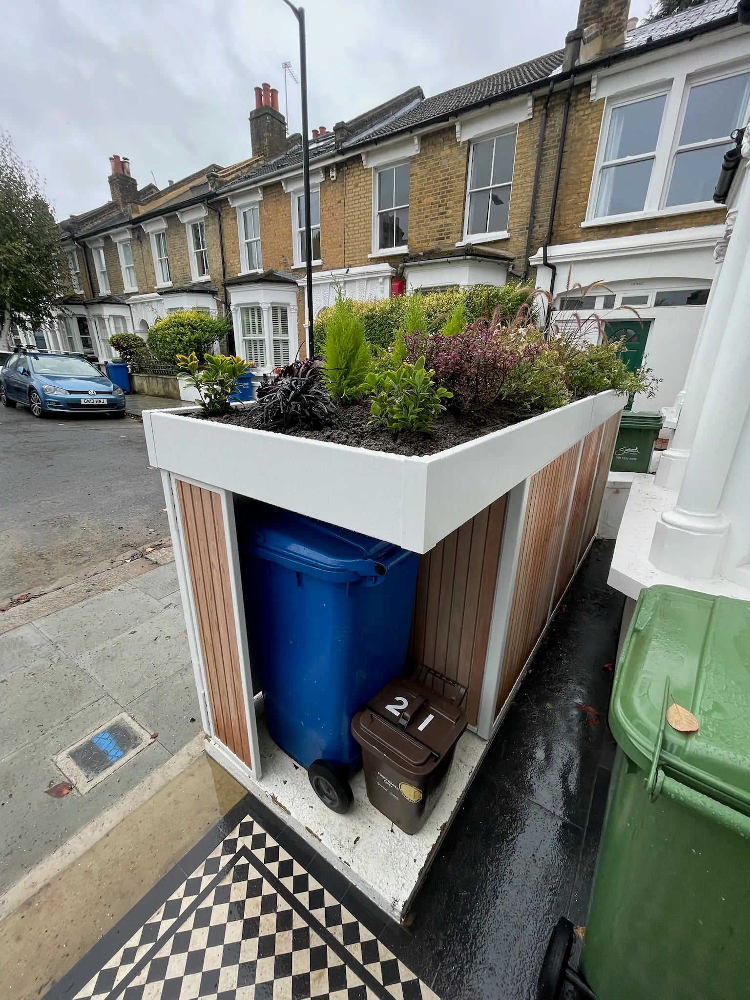 View from house entrance looking onto compact bike store with planted roof in redesigned London front garden.
