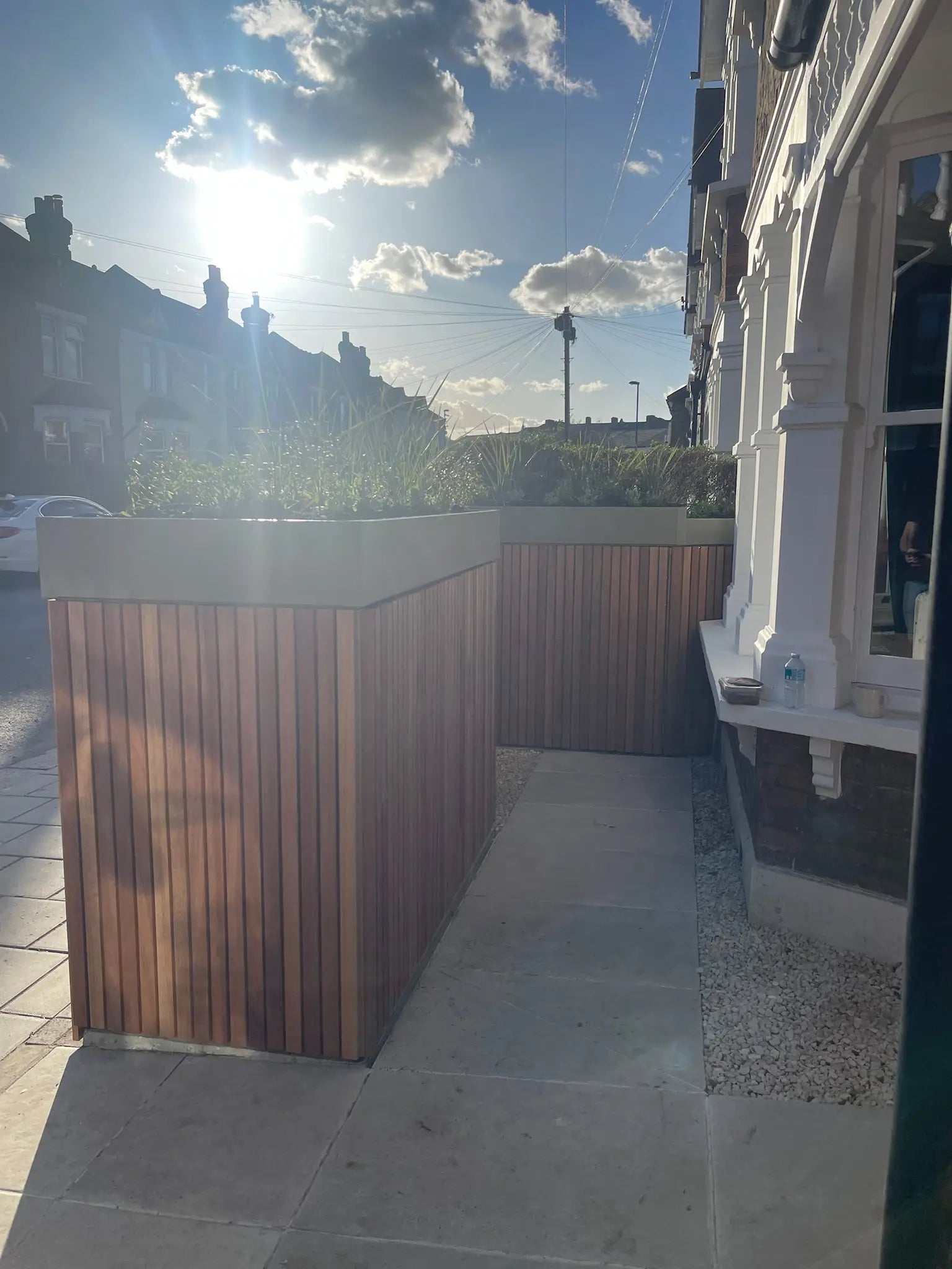 View from entrance path showing decluttered front garden with open planted space and integrated boundary storage