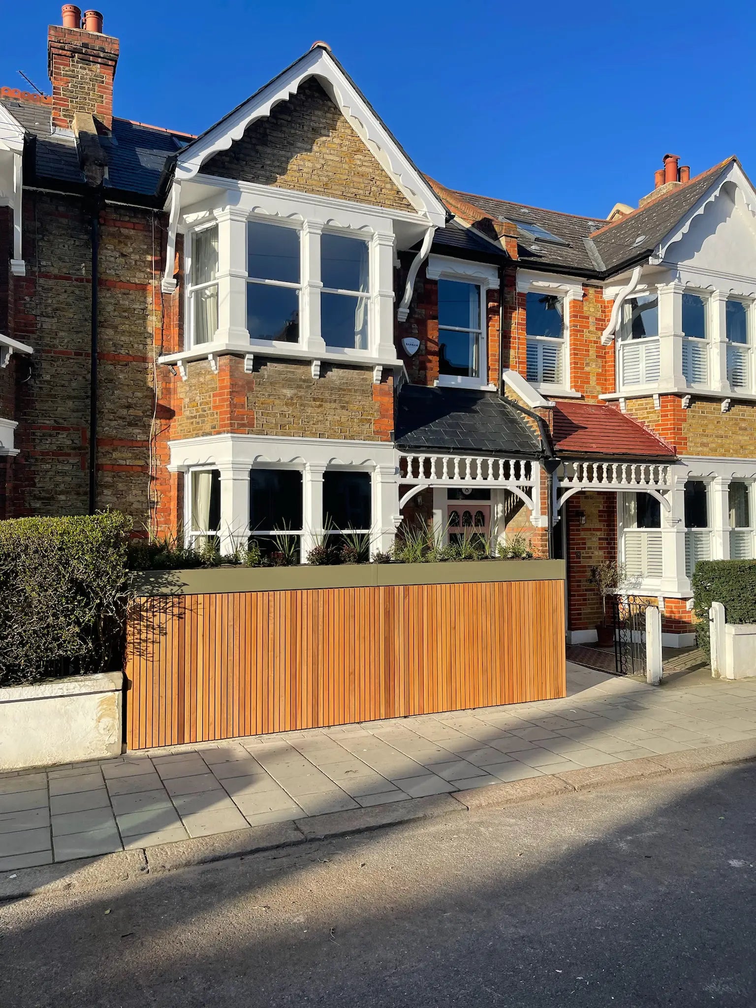 Street view from the left showing front garden boundary redesign with integrated storage and planted roof
