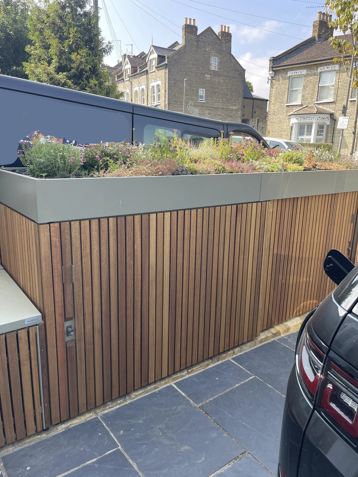 planted roof on top of a bespoke cycle and refuse store with large sliding doors