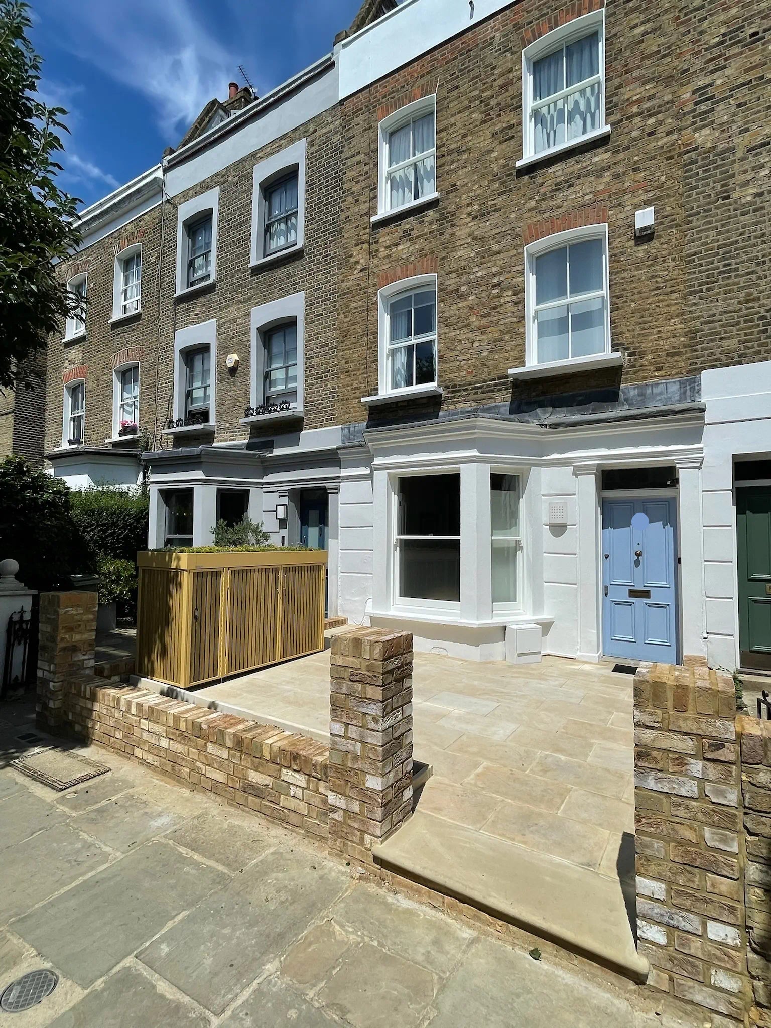 Full front garden view of green roof bin and parcel store integrated with landscaping.