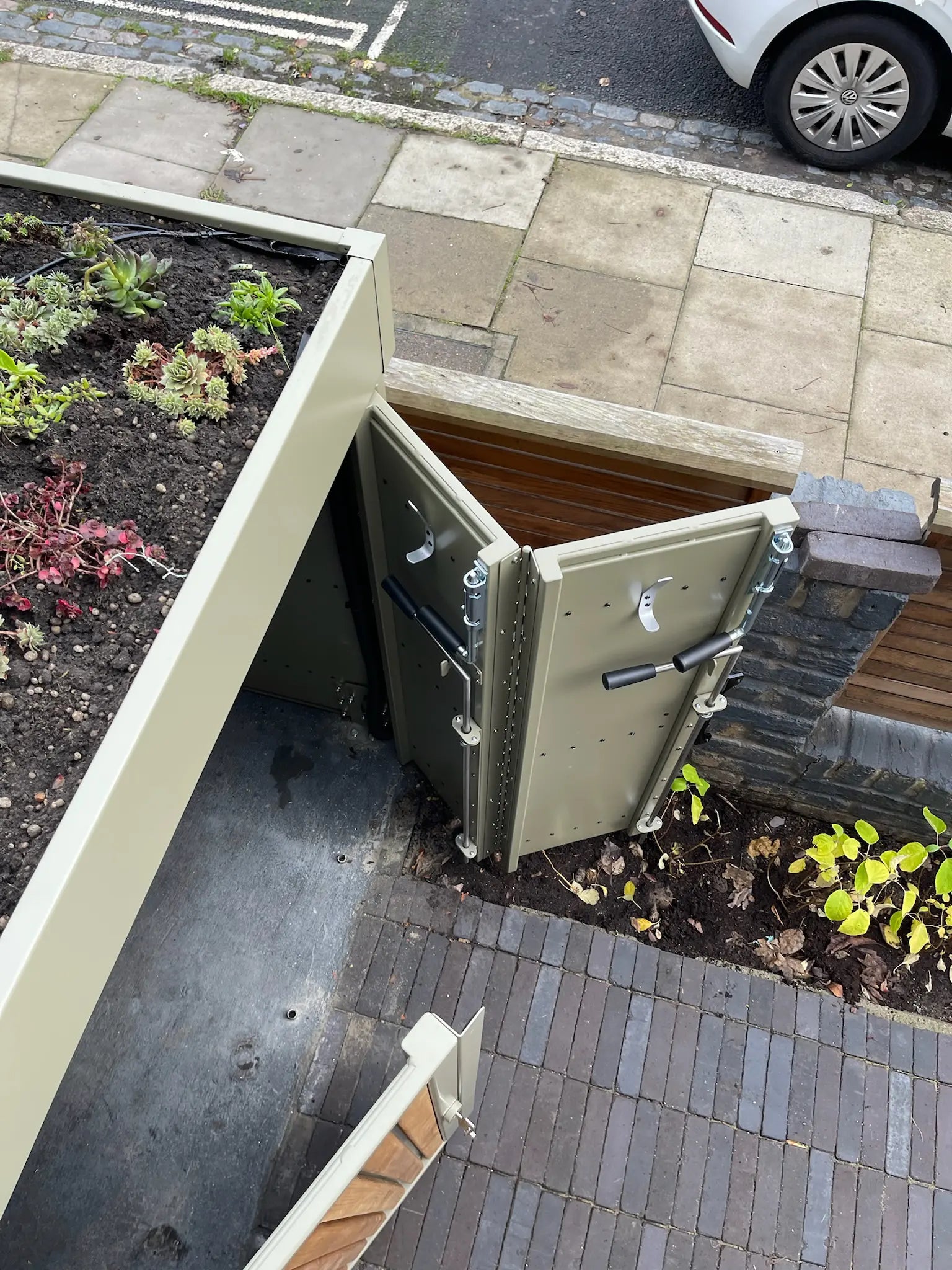 Double-hinged bike-store door designed to protect planting bed in London front garden