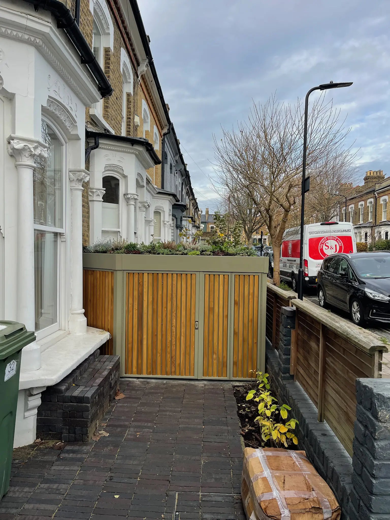 Front view of London garden storage with large hinged door and protective side planter