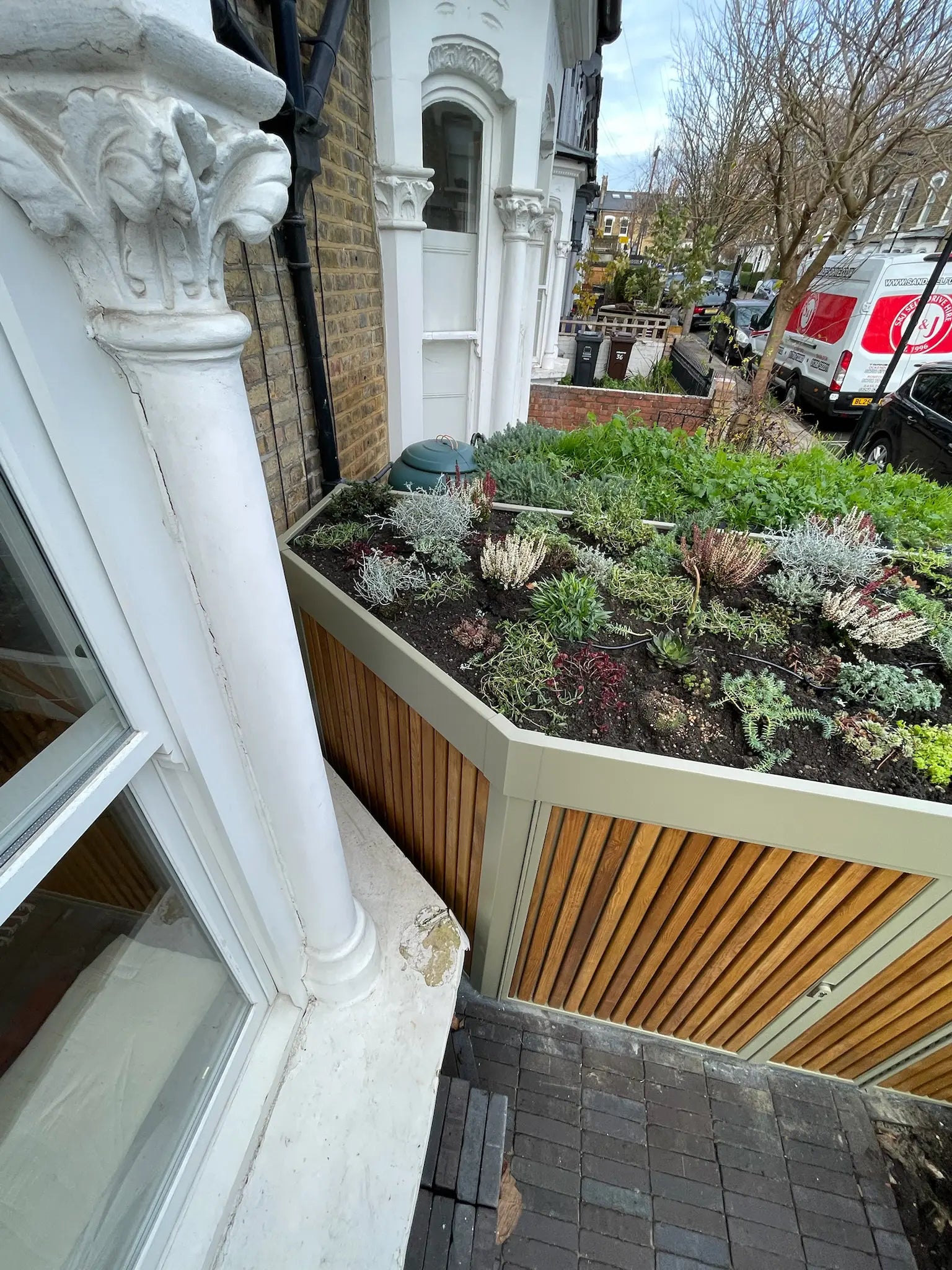 Detail of sedum green roof wrapping around bay window sill on London side-storage solution