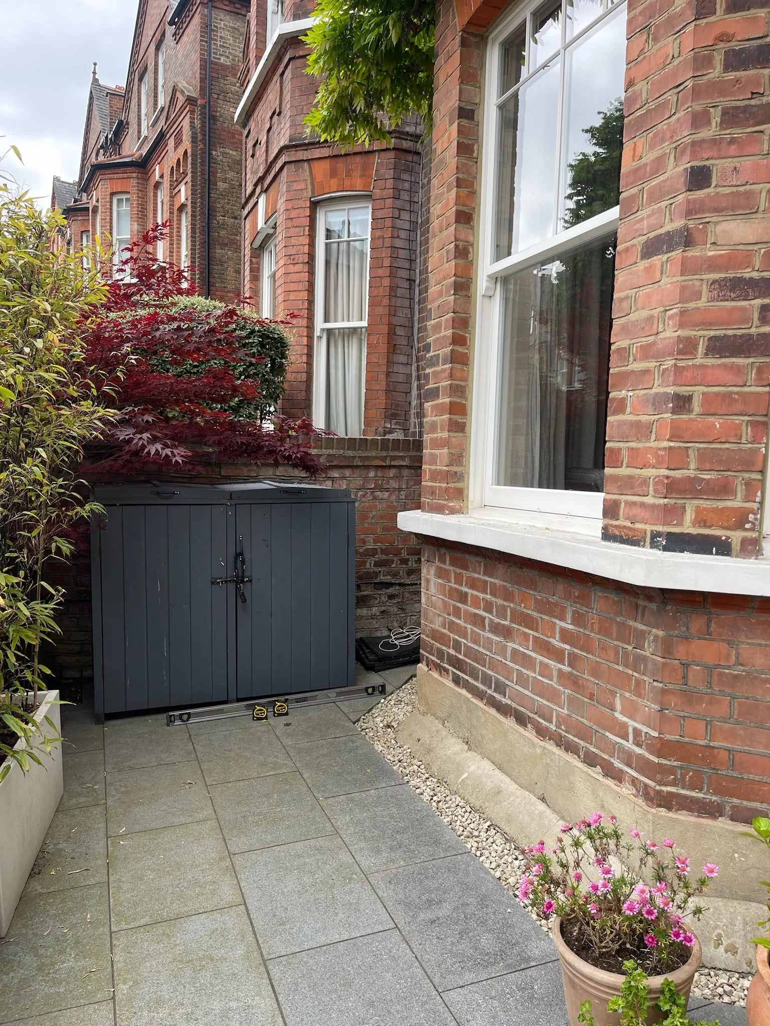 Old timber bike shed in London front garden, too small and insecure for growing family’s bicycle storage needs.