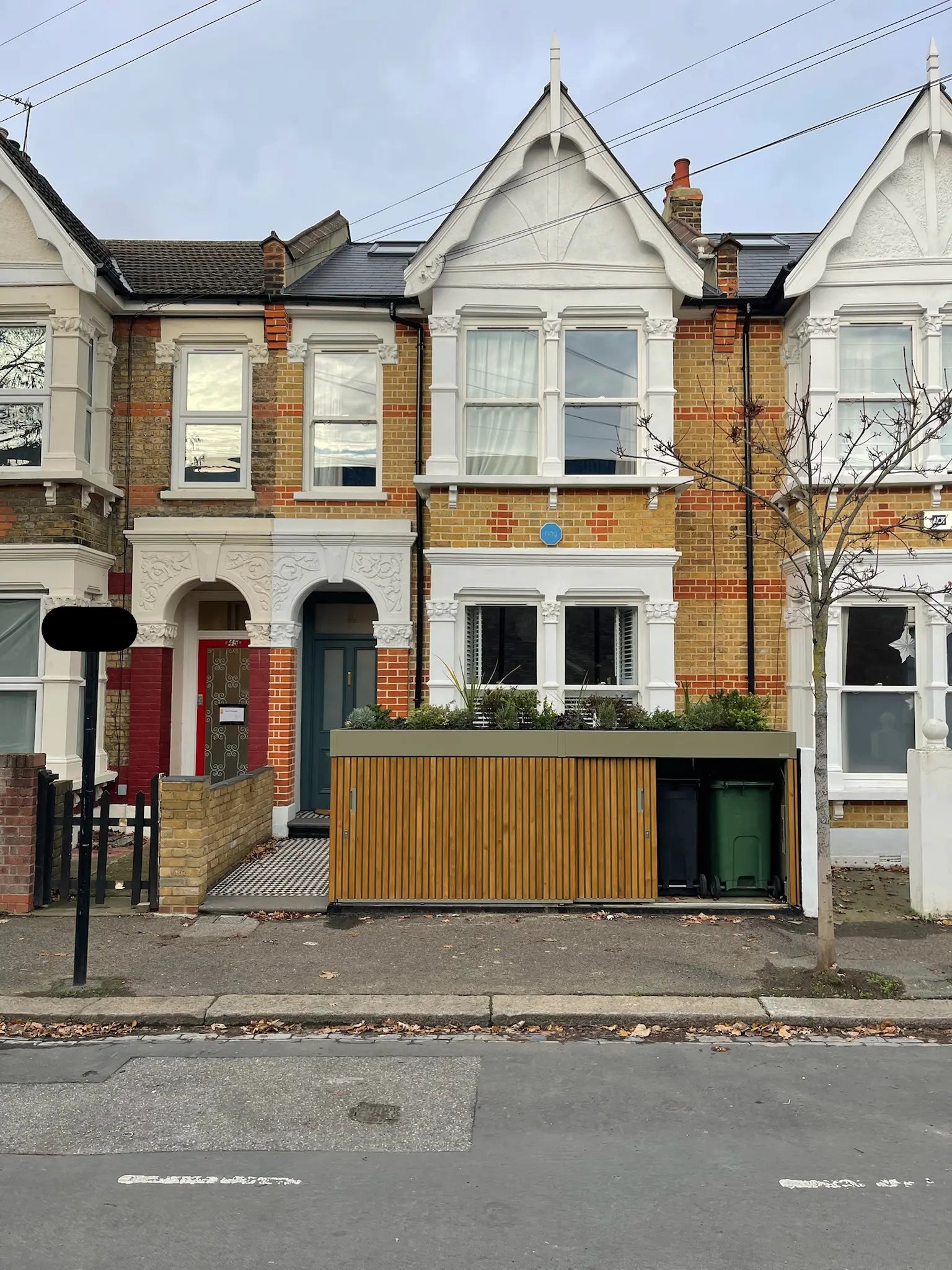 Front view of olive grey bin store with walnut-stained timber cladding, showing concealed wheelie bin storage in a London front garden