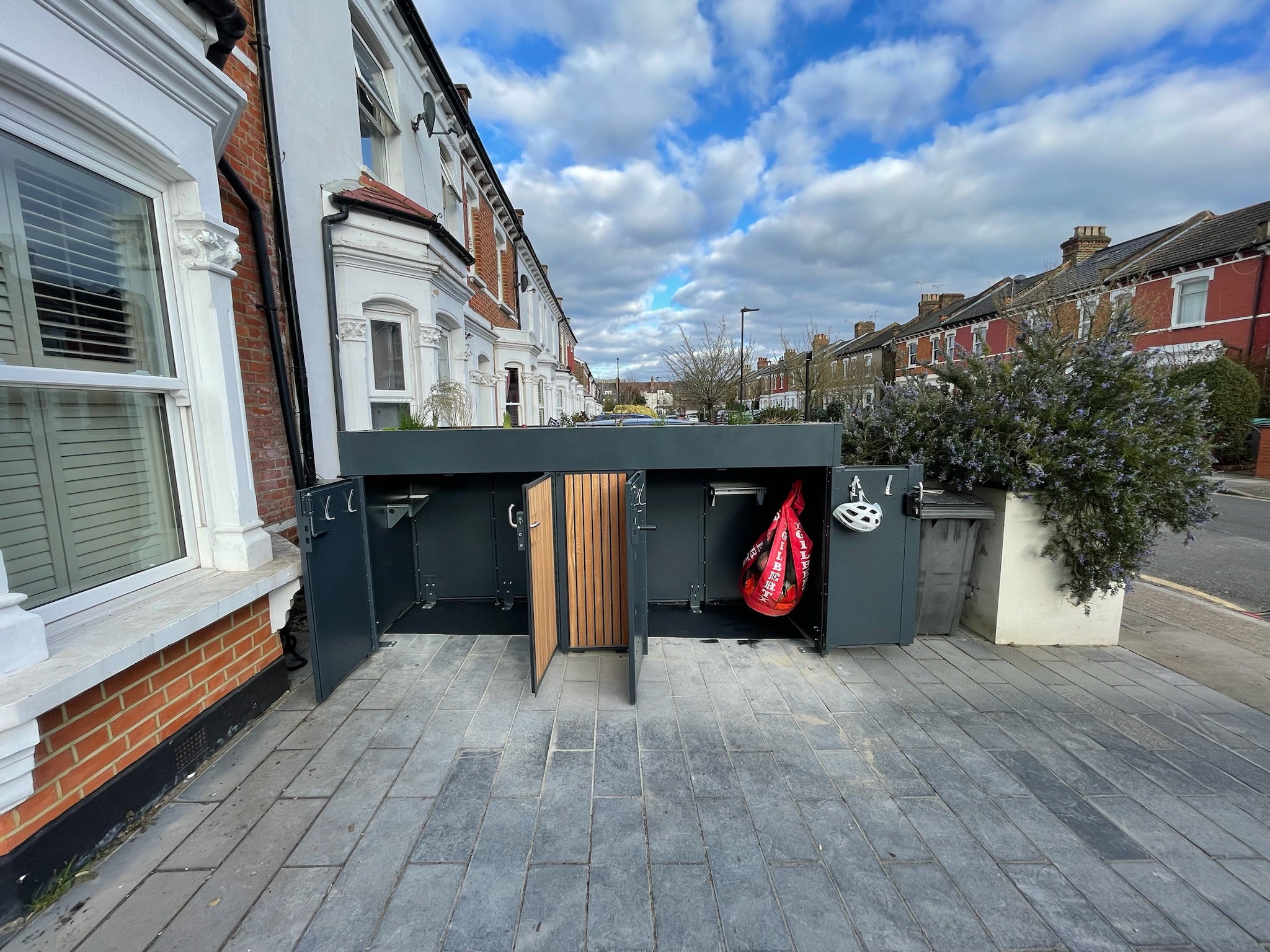 Front view of an open bike storage unit with both sides double hinged doors and a deep planted green roof, showcasing secure storage for multiple bikes.