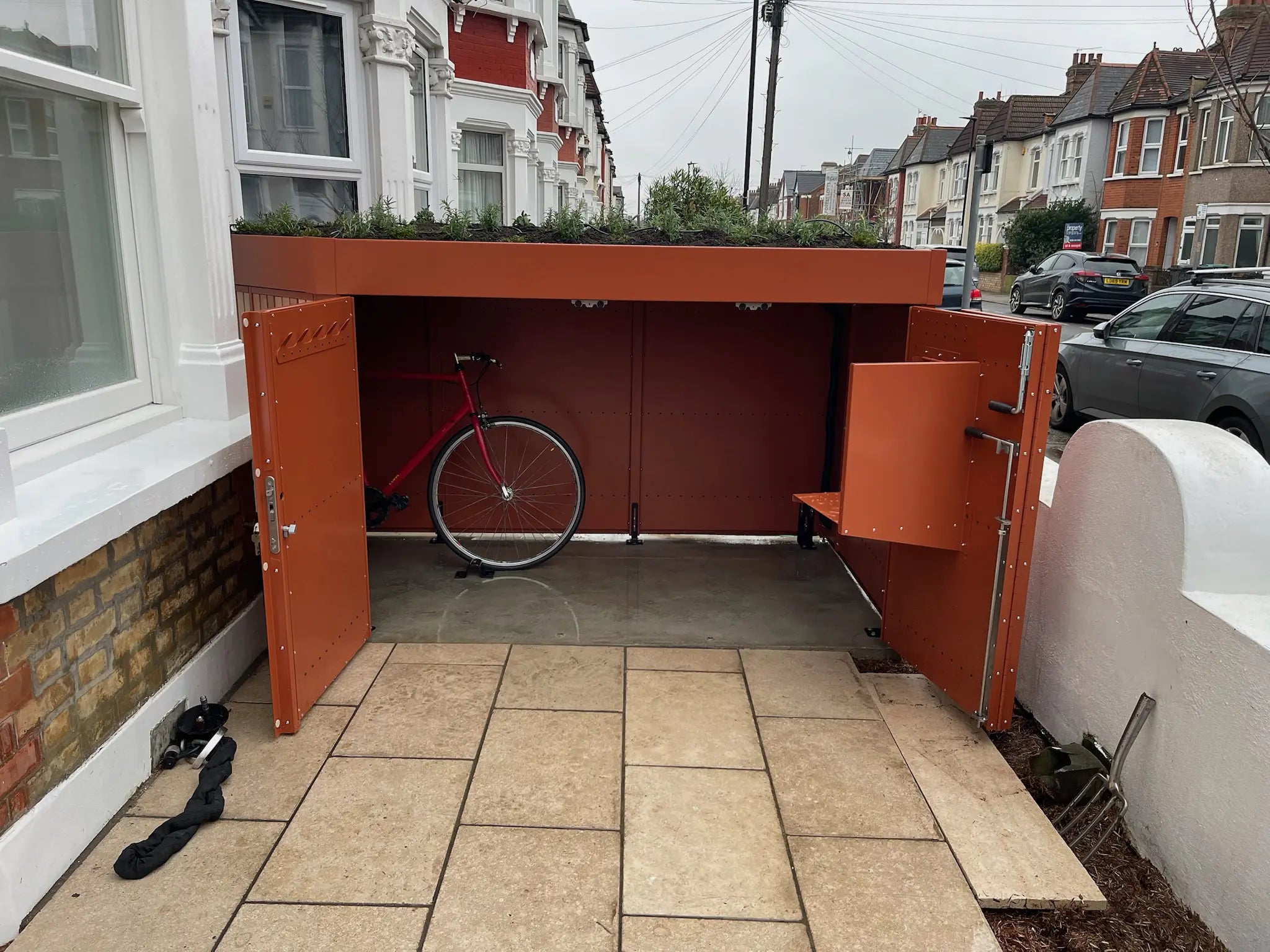 Wide open bike storage and parcel box in a London terraced home, providing secure family cycle storage.
