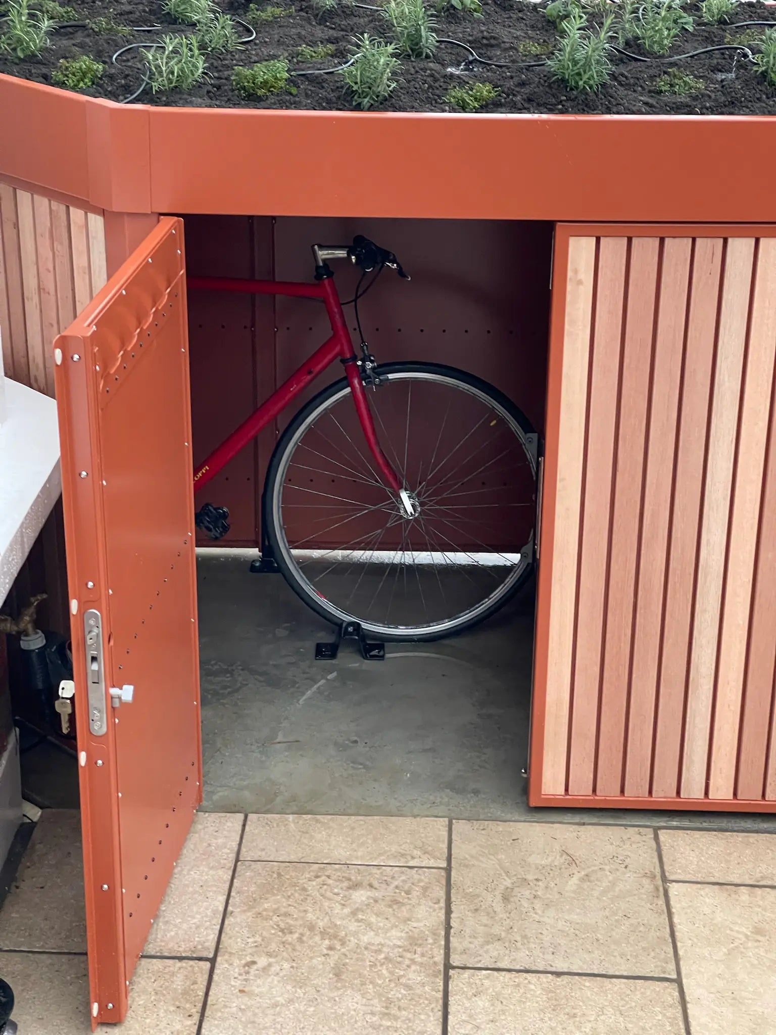 Detail of secure front garden bike storage with bicycle inside, suitable for London terraced homes.