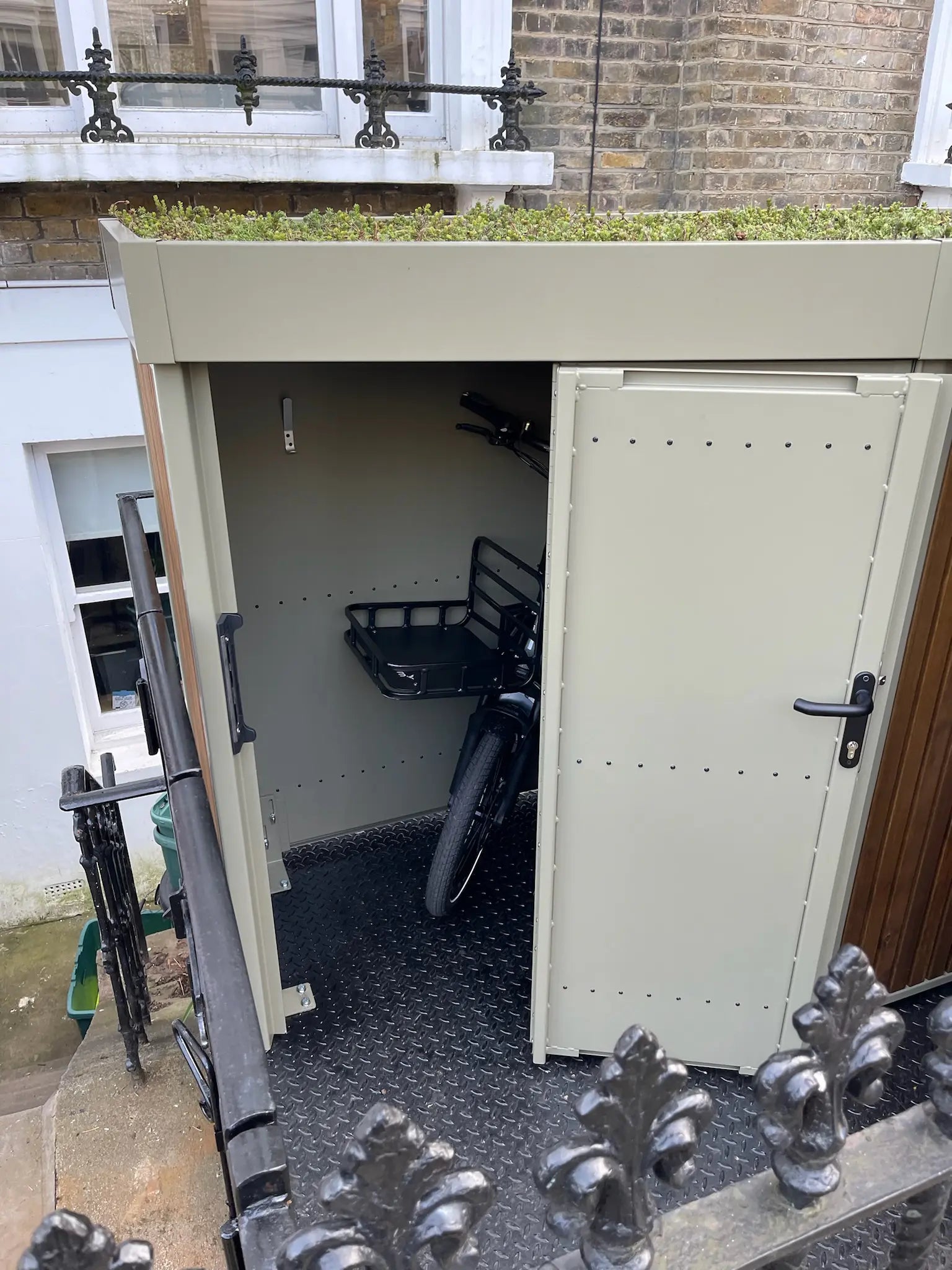 Interior view of the bespoke Verde cargo bike shed with one door open and cargo bike inside

