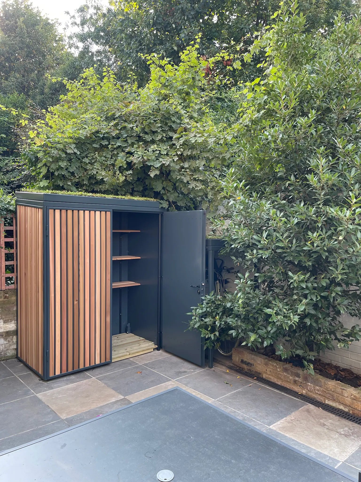 Overview of the Verde Uno bike shelter and open garden shed with shelves visible inside